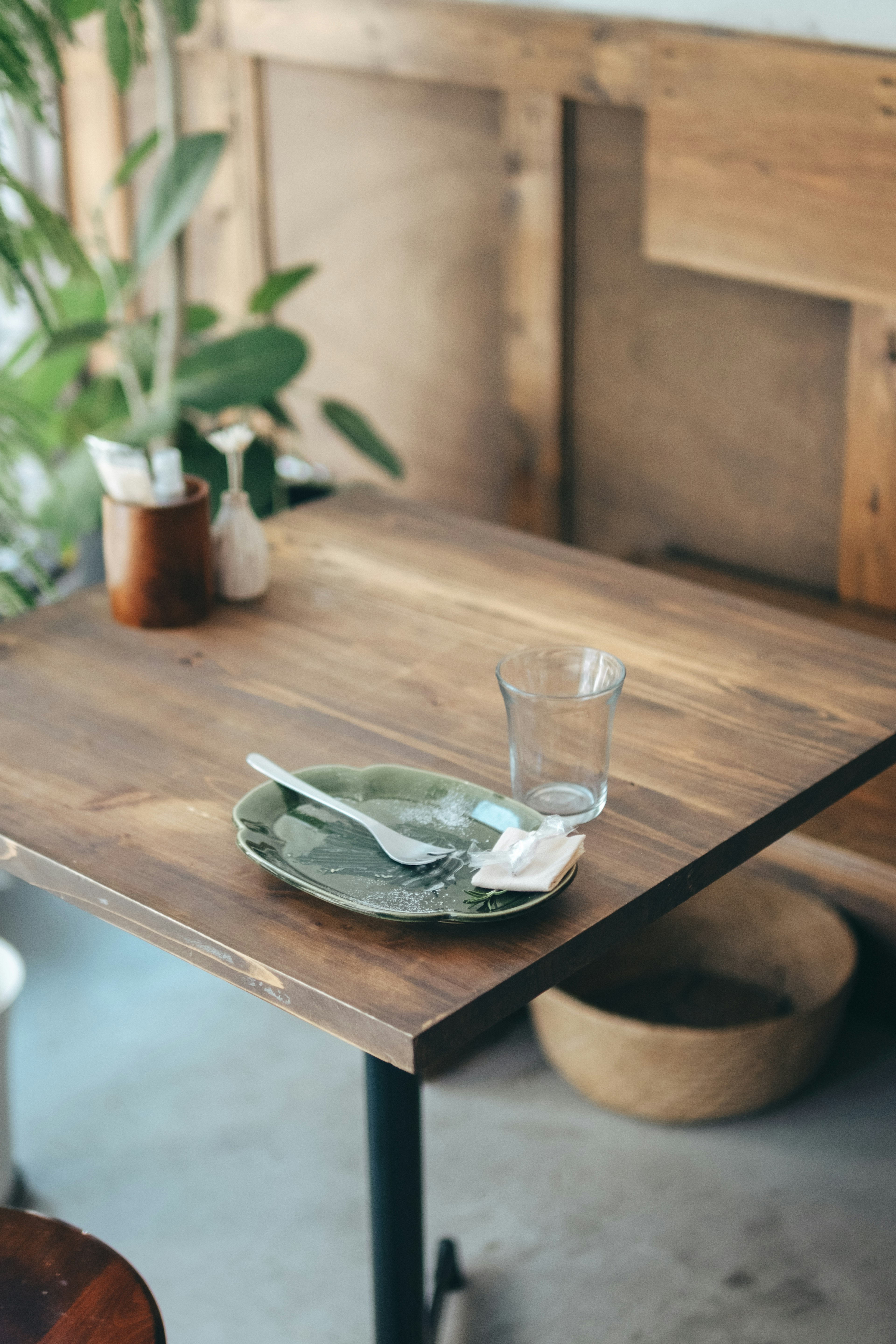 Wooden table with green plate and cutlery in a cafe interior