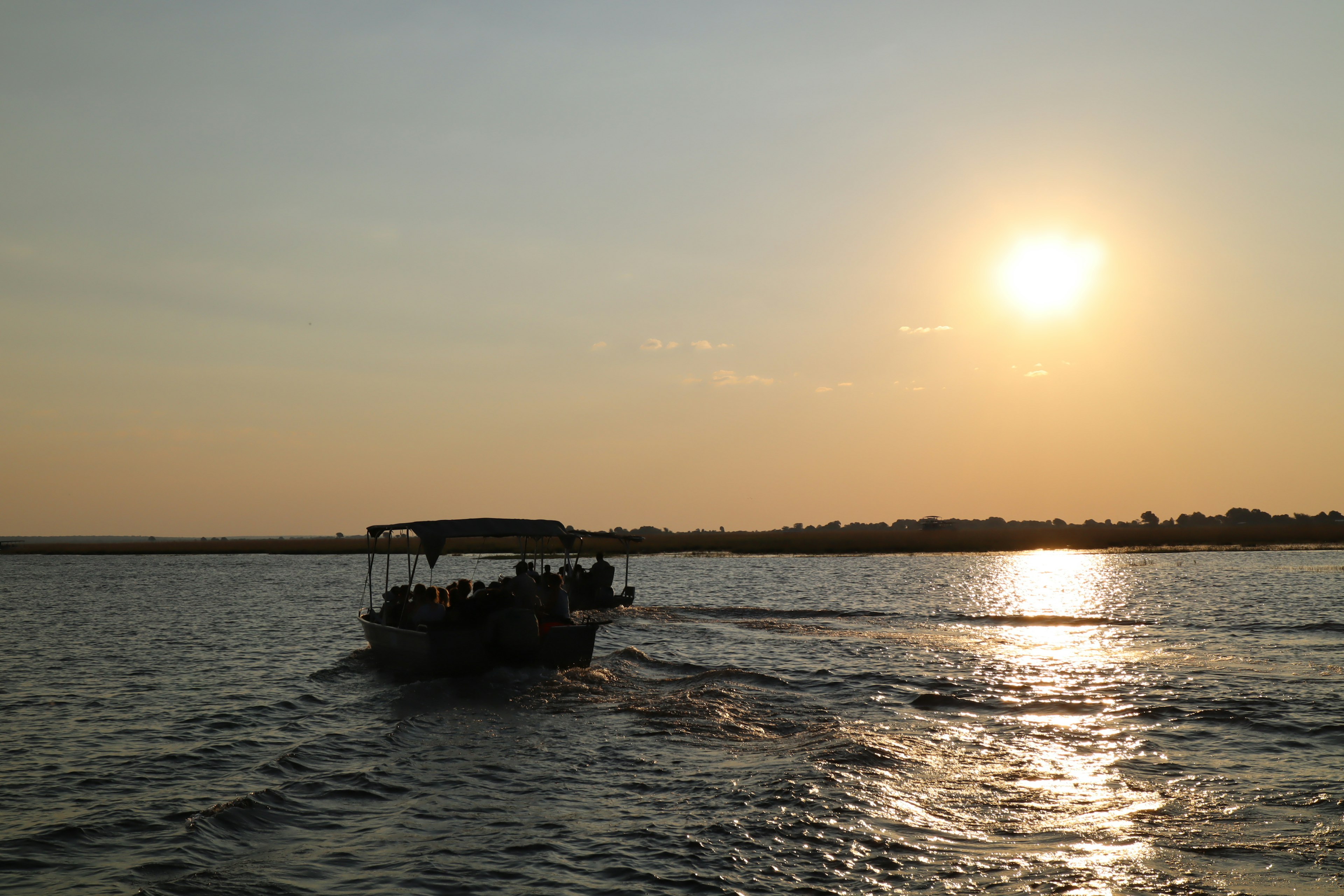 A boat moving on the water with the sun setting in the background