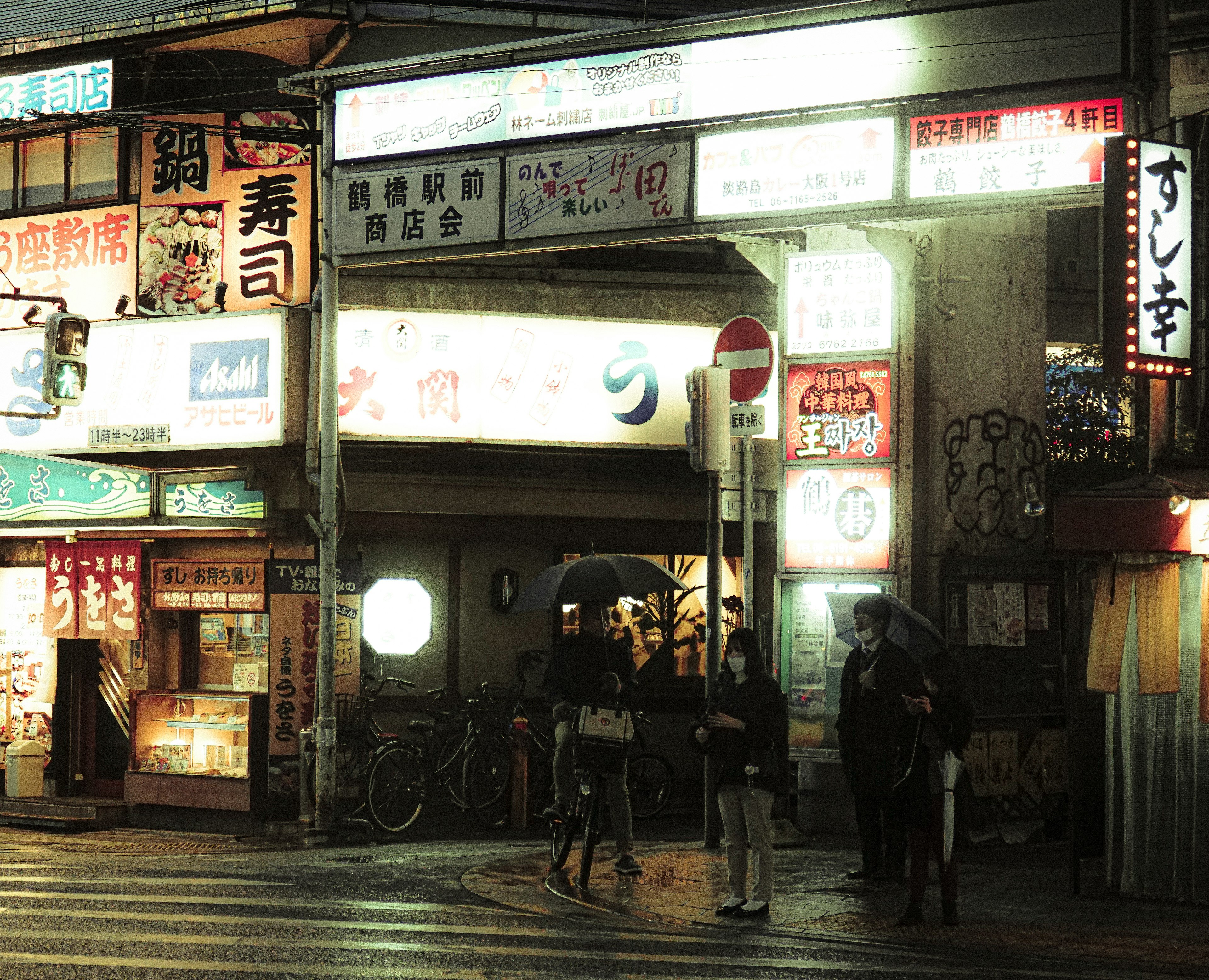 Night street corner with restaurant signs and people