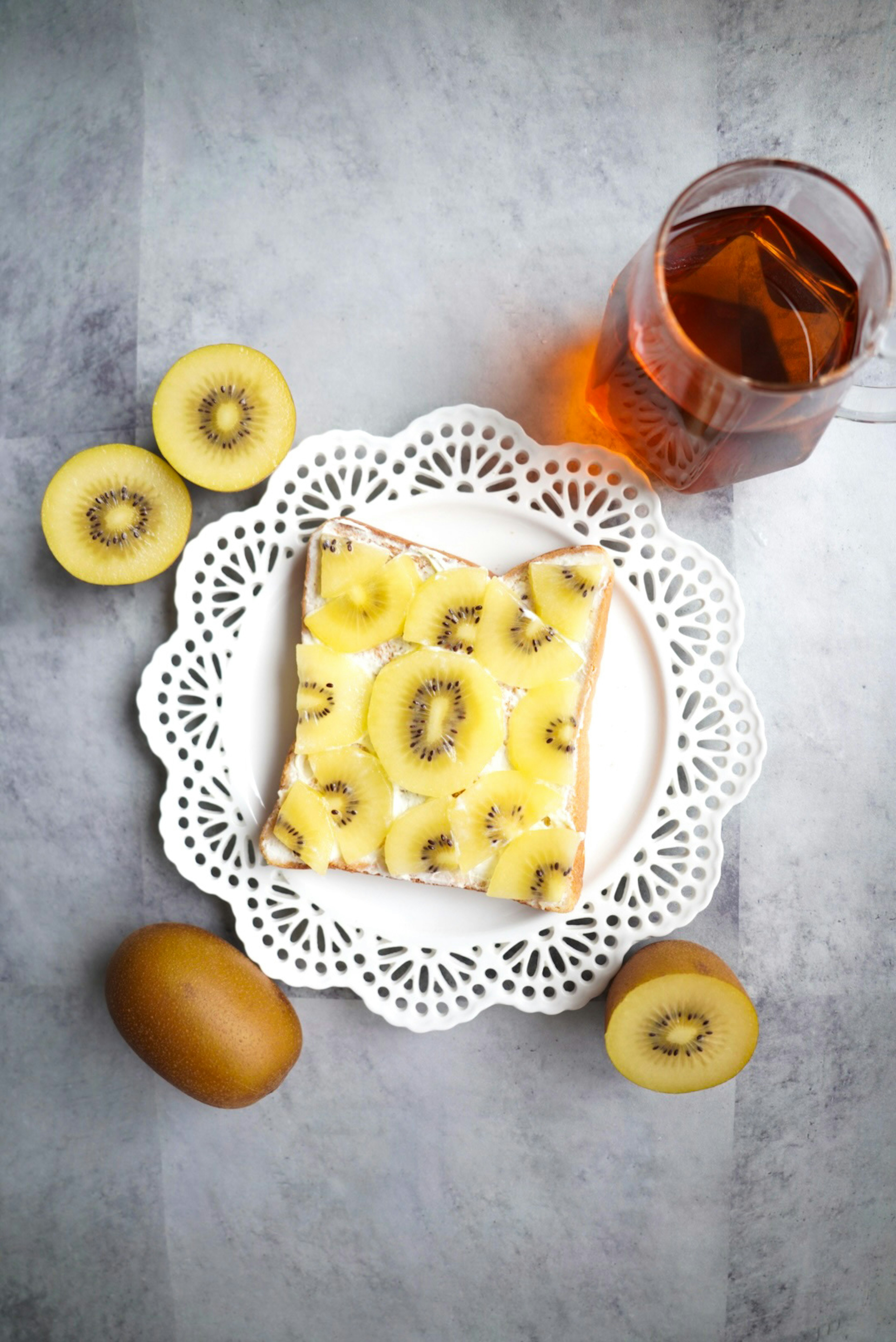 Roti dengan kiwi dan krim keju disajikan di piring putih dekoratif