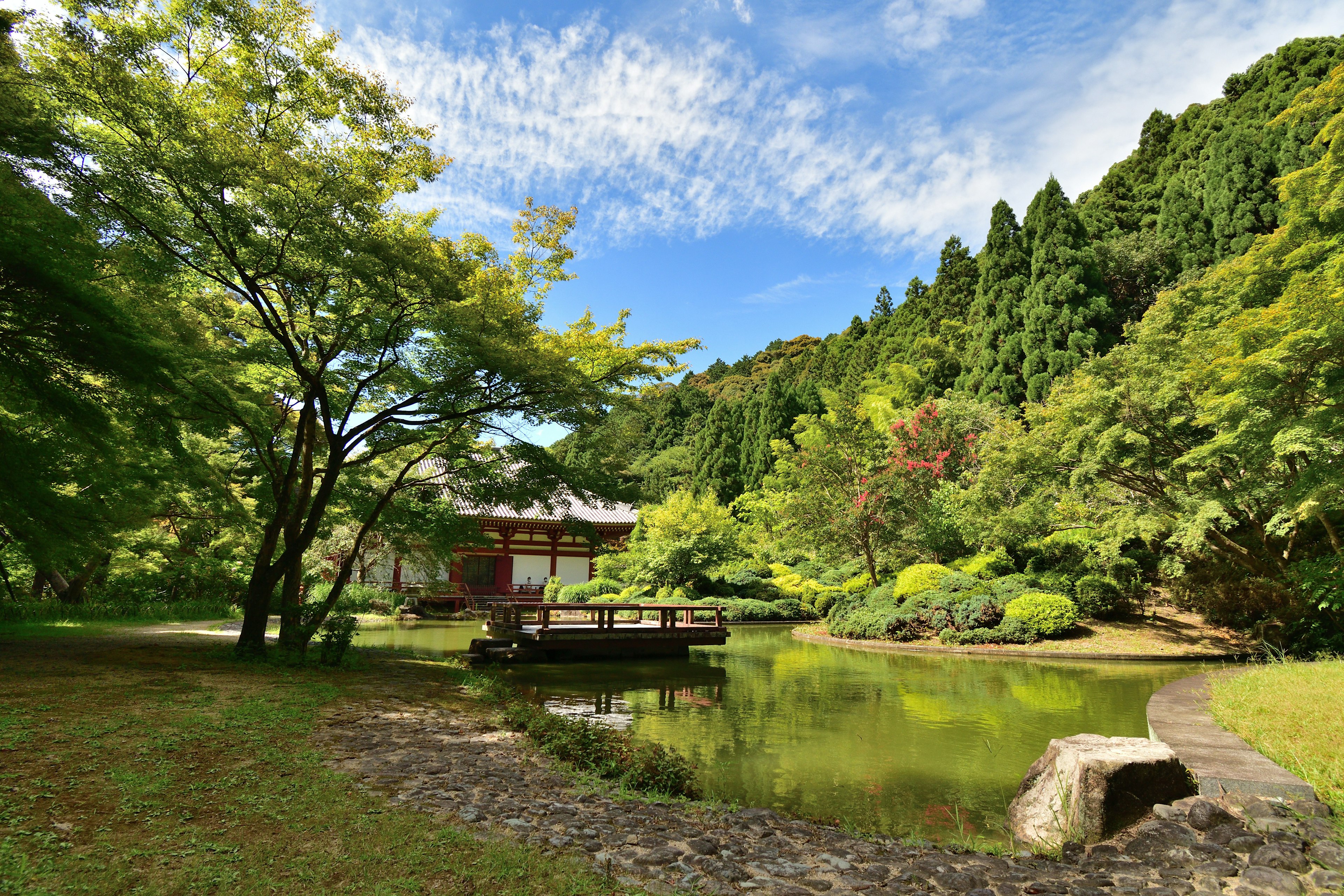 Malersicher japanischer Garten mit Teich und Bäumen unter blauem Himmel