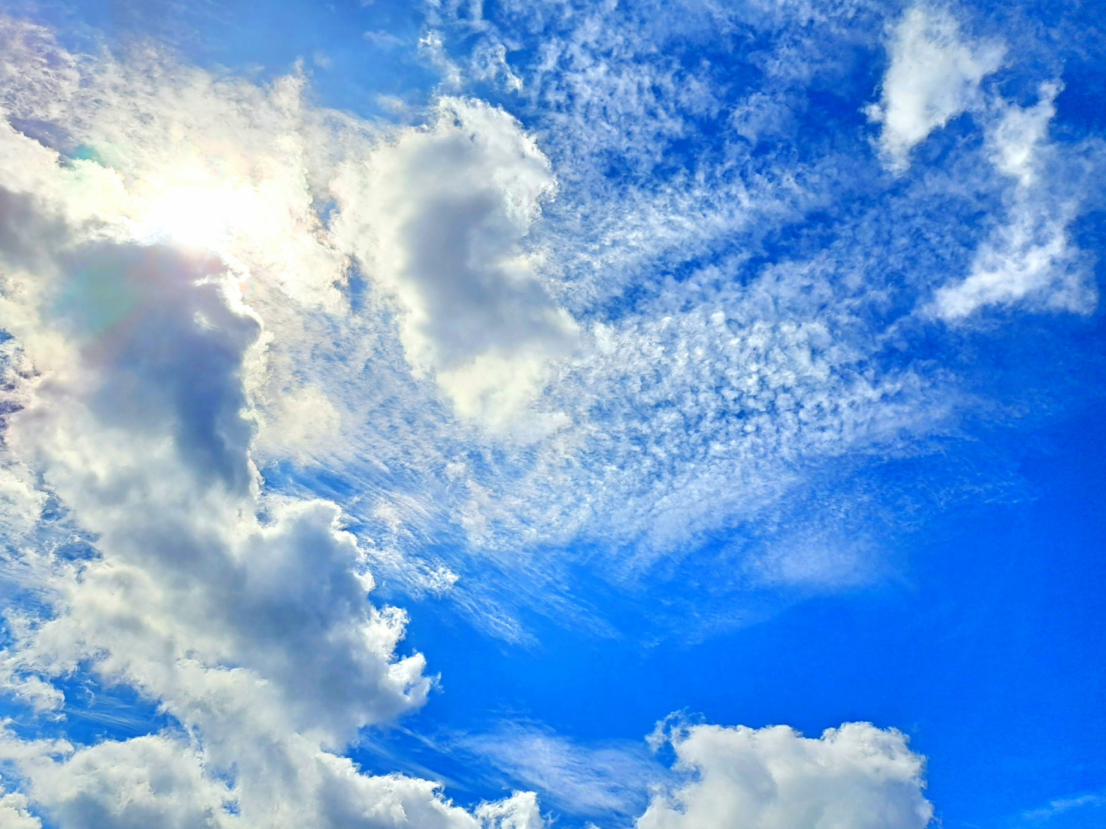 White clouds floating in a blue sky with sunlight reflections