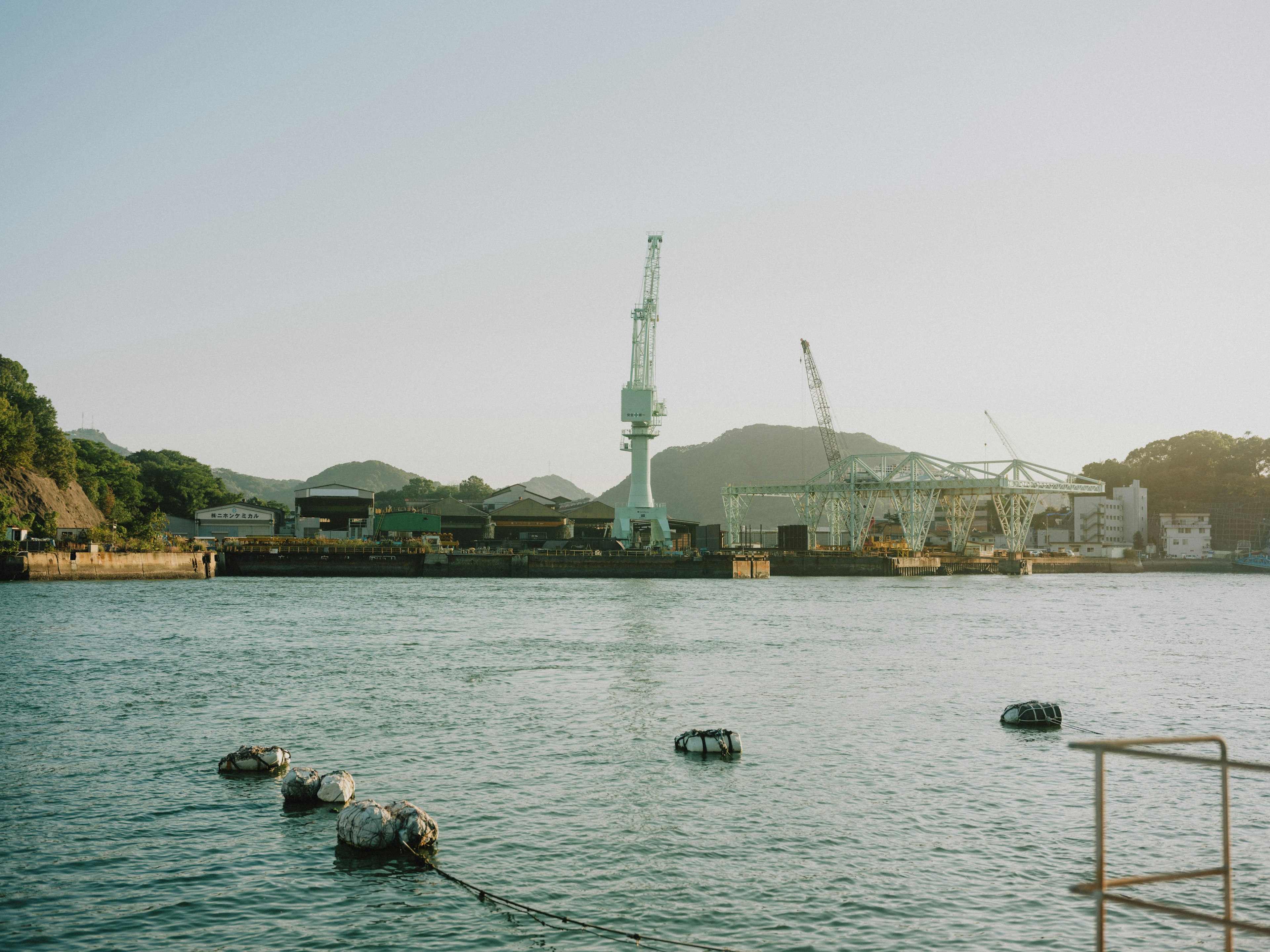 海に浮かぶボートと工場のクレーンの風景