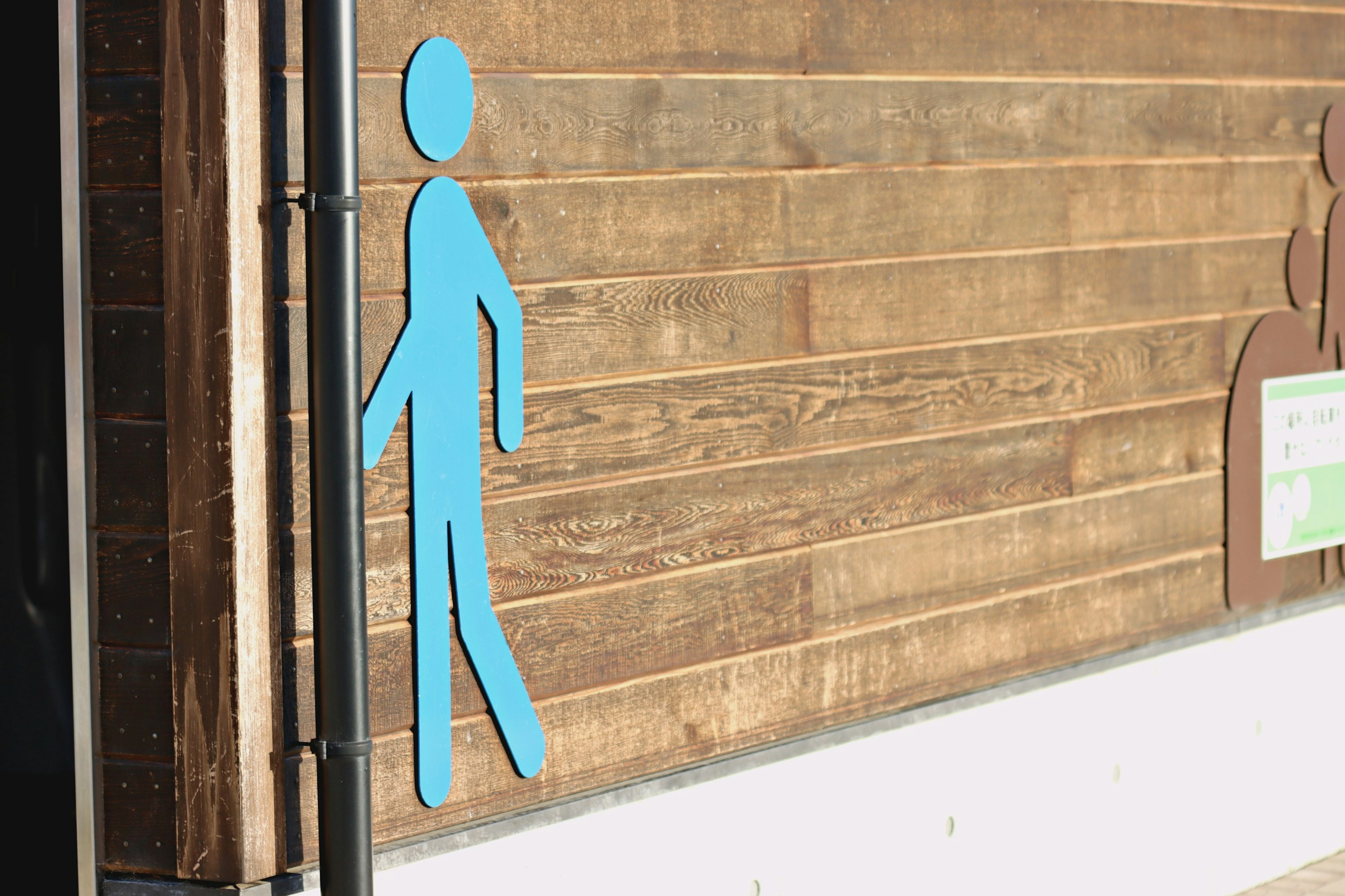 Blue male restroom sign on wooden wall