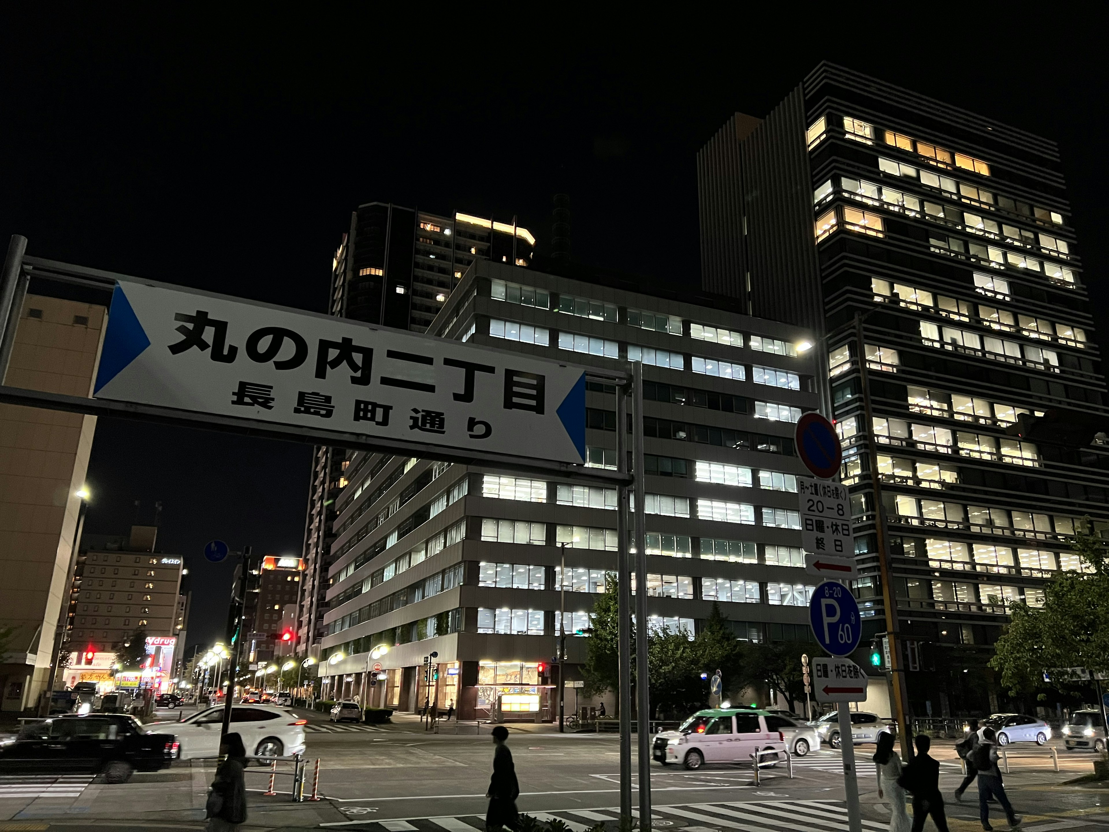 Intersection at night featuring a street sign and modern buildings