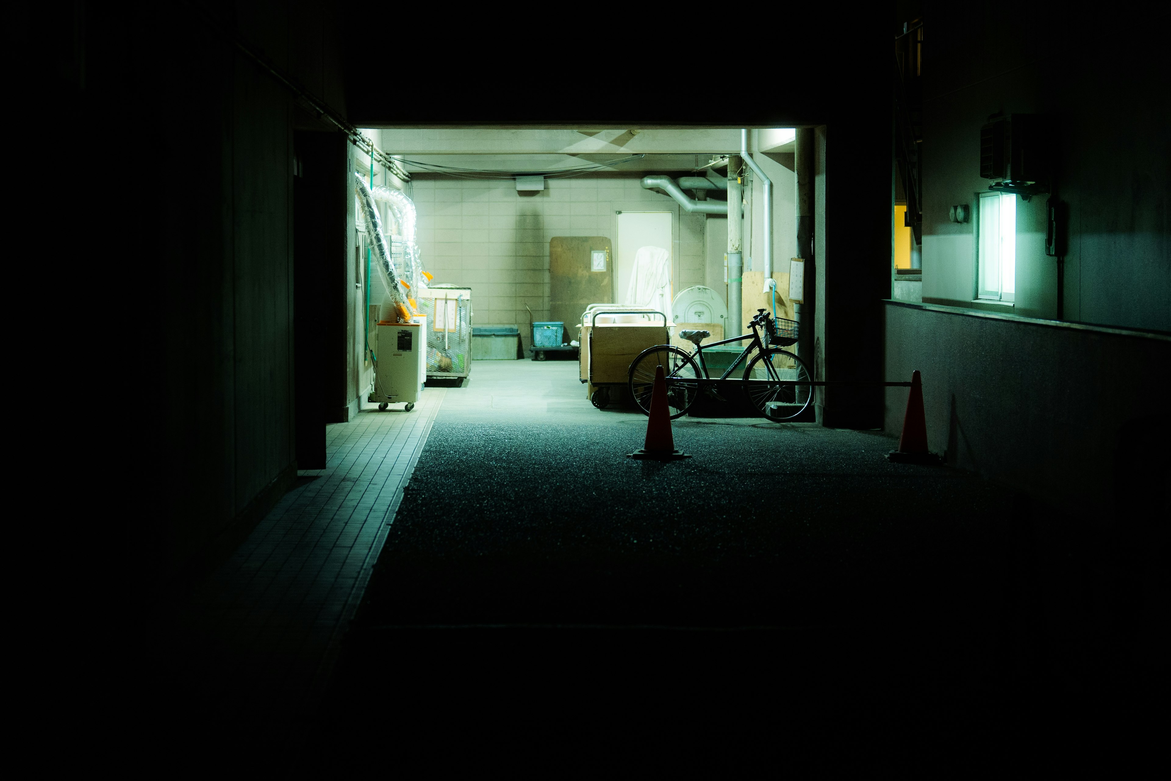 Dark corridor leading to a brightly lit room with various objects