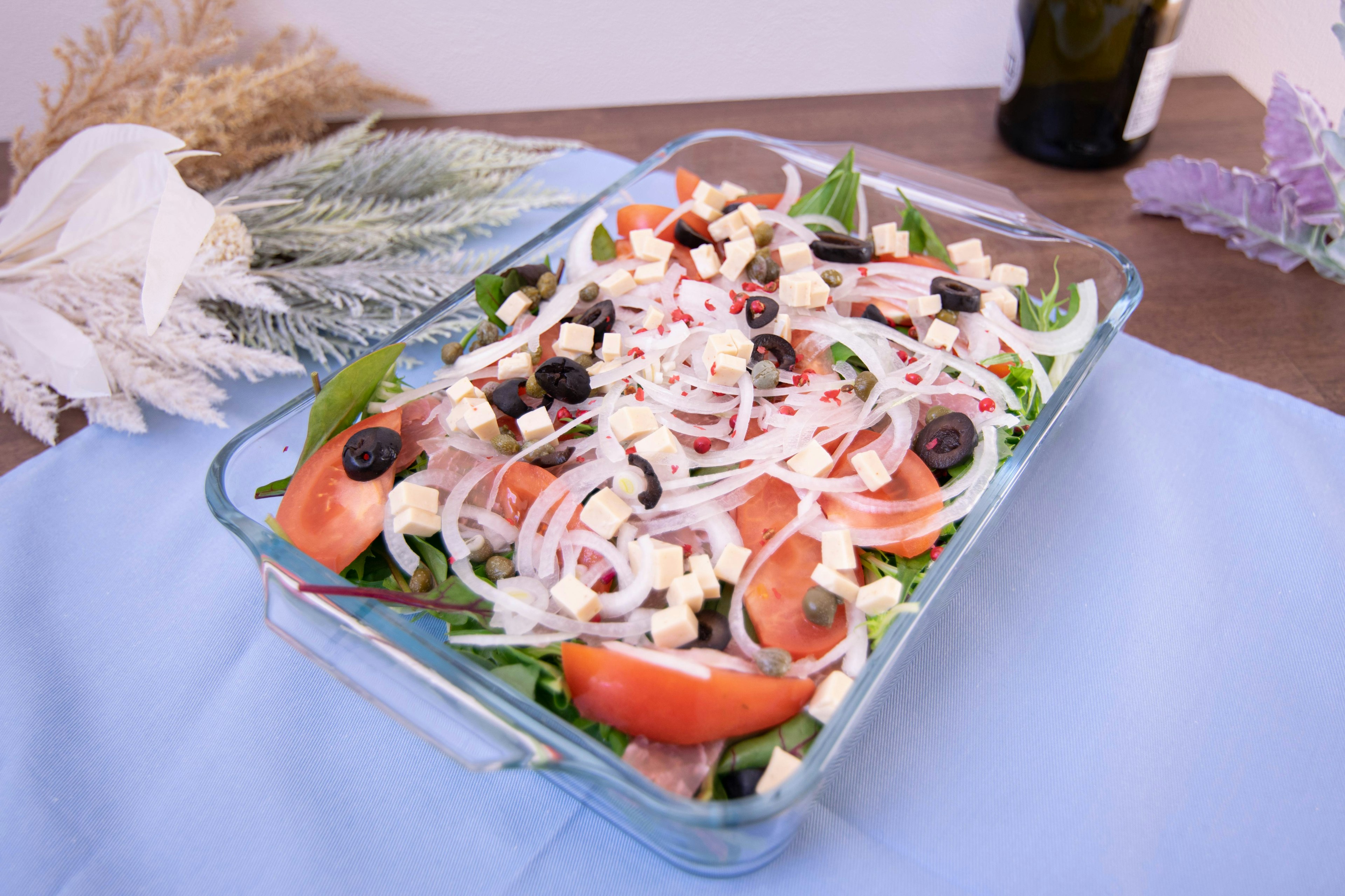 Plat en verre rempli de salade fraîche avec des tomates et des olives