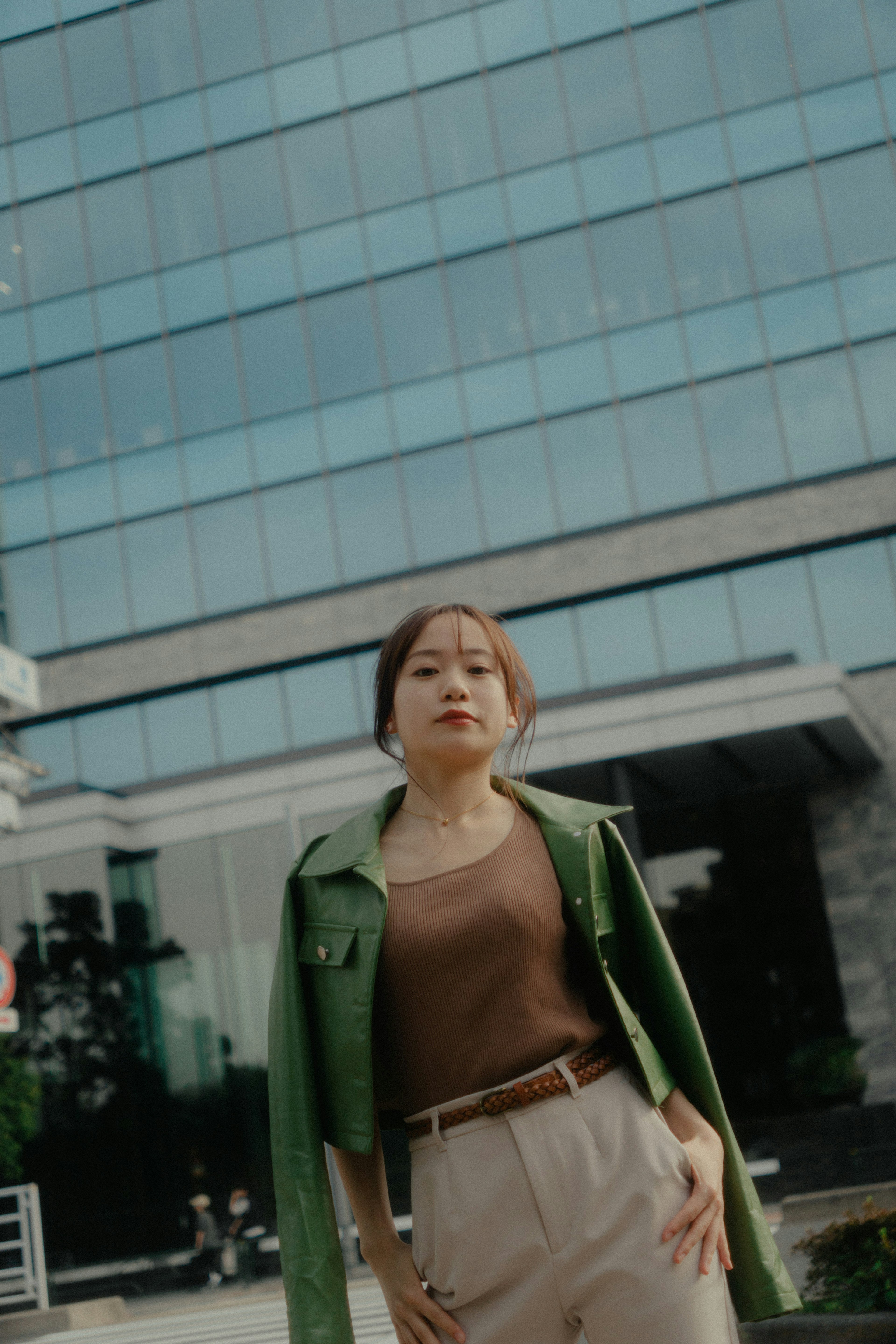 A woman in a green jacket stands in front of a building