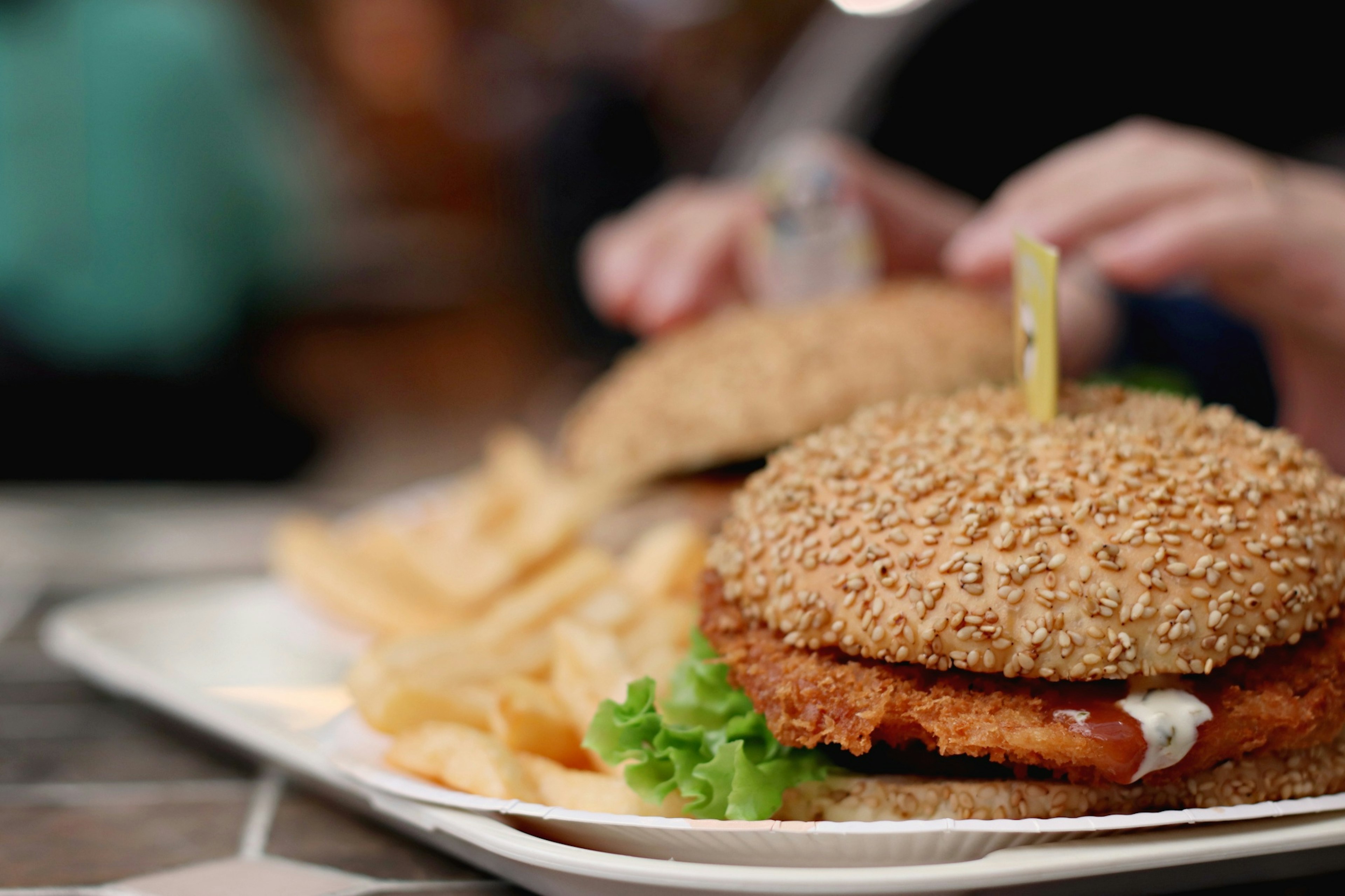 Sesambun-Burger mit knusprigem Hähnchenpatty und Salat serviert mit Pommes frites