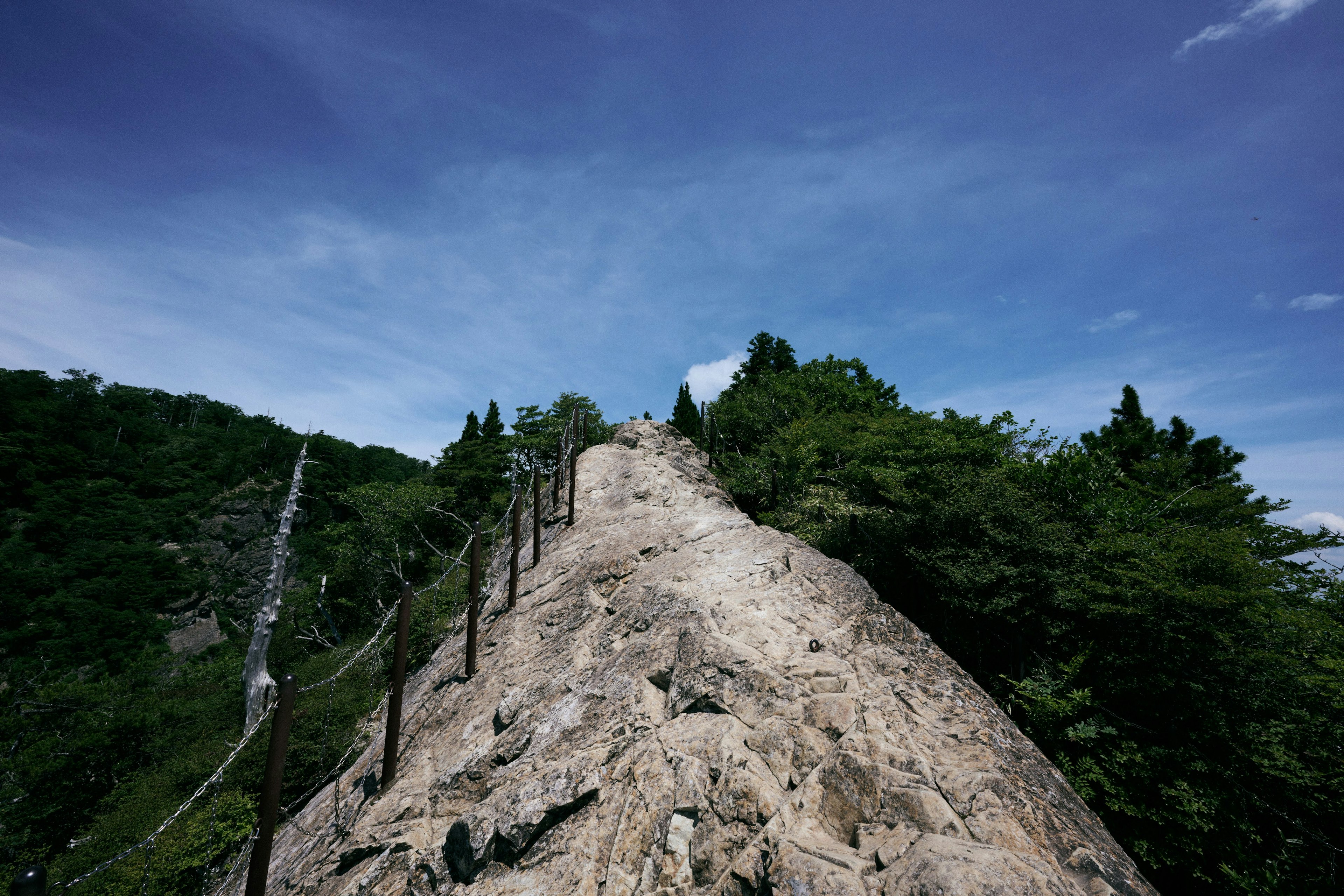 険しい岩山と青空の風景 鎖のついた登山道