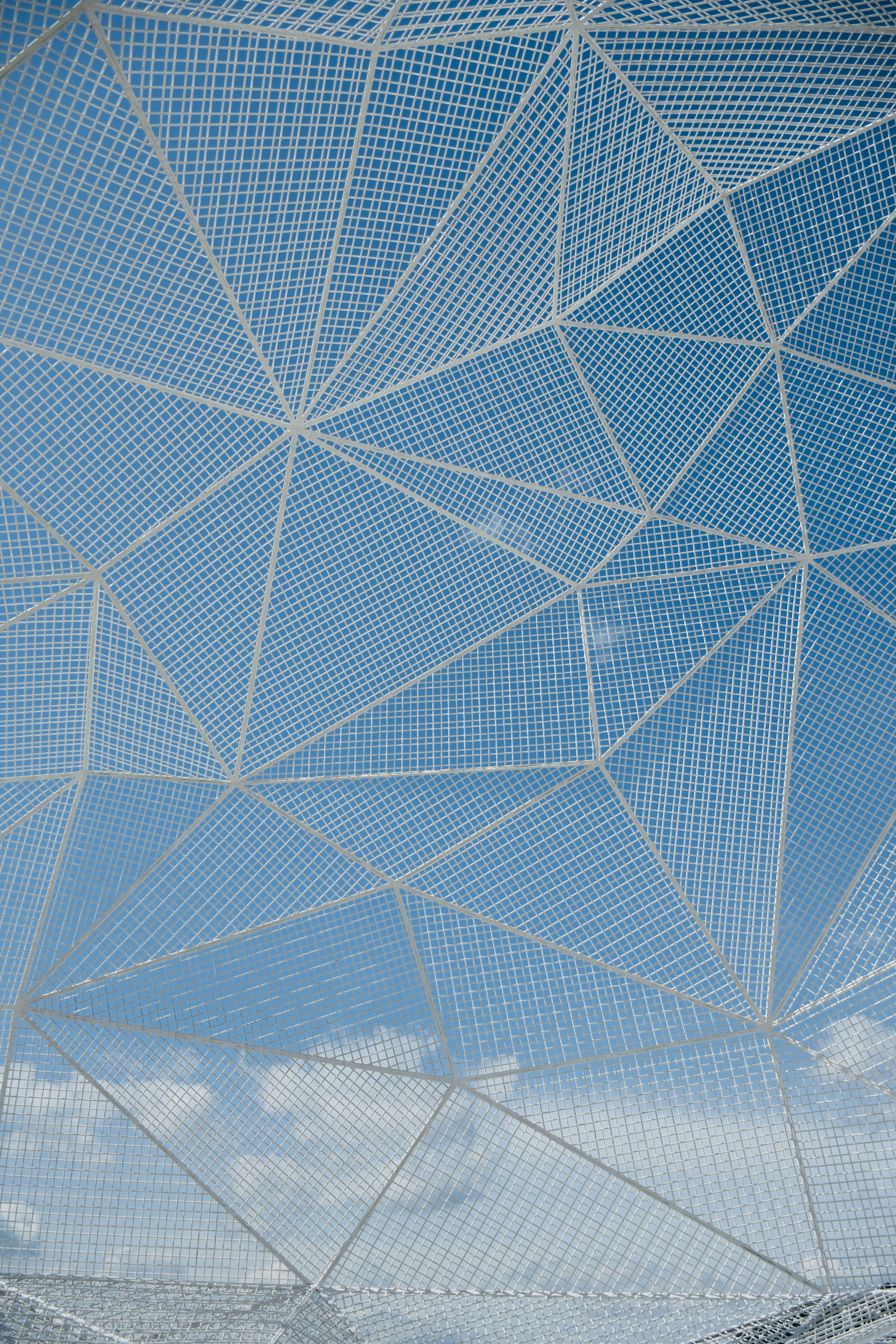 Geometric design of white mesh pattern against a blue sky