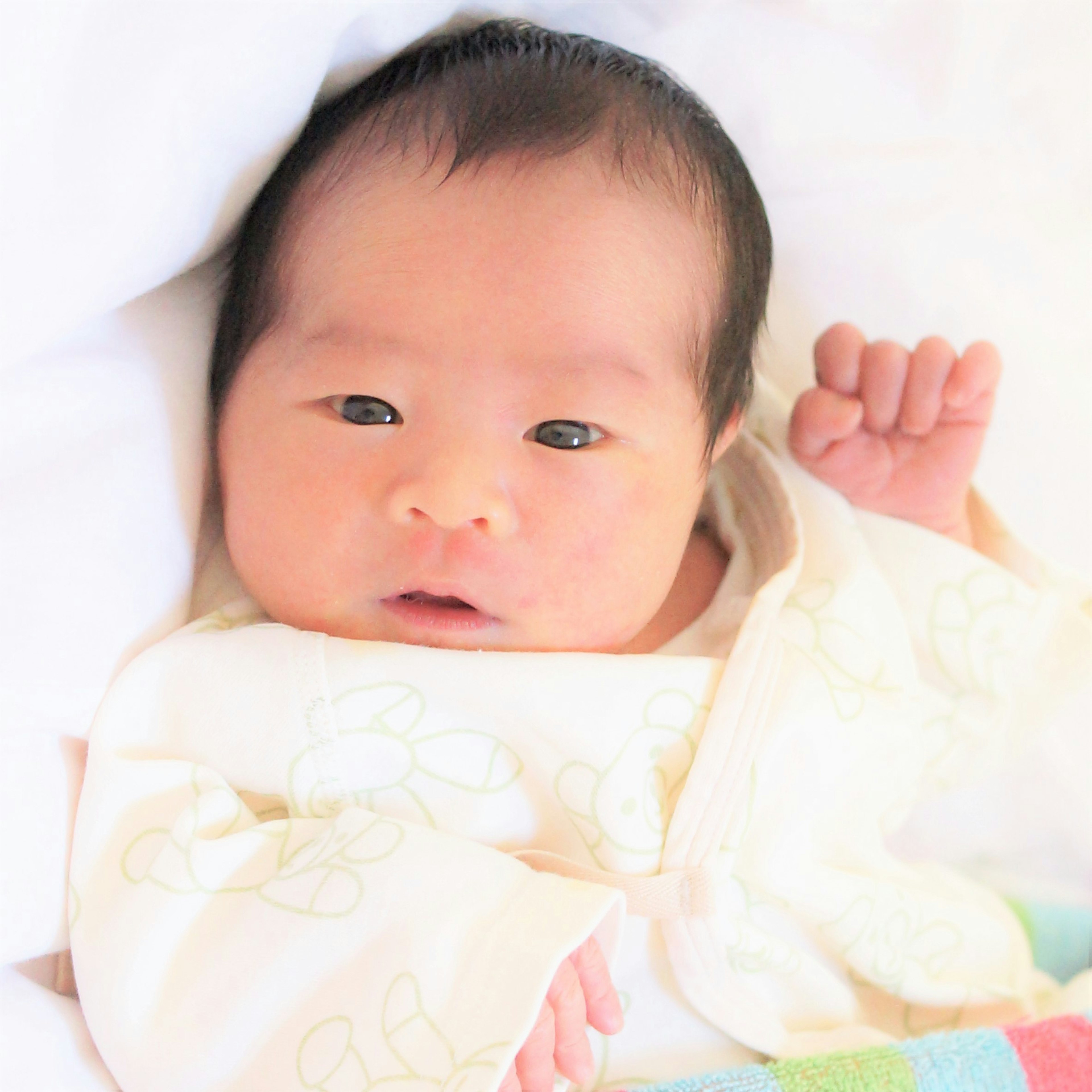 A cute baby wearing a white outfit with a gentle expression