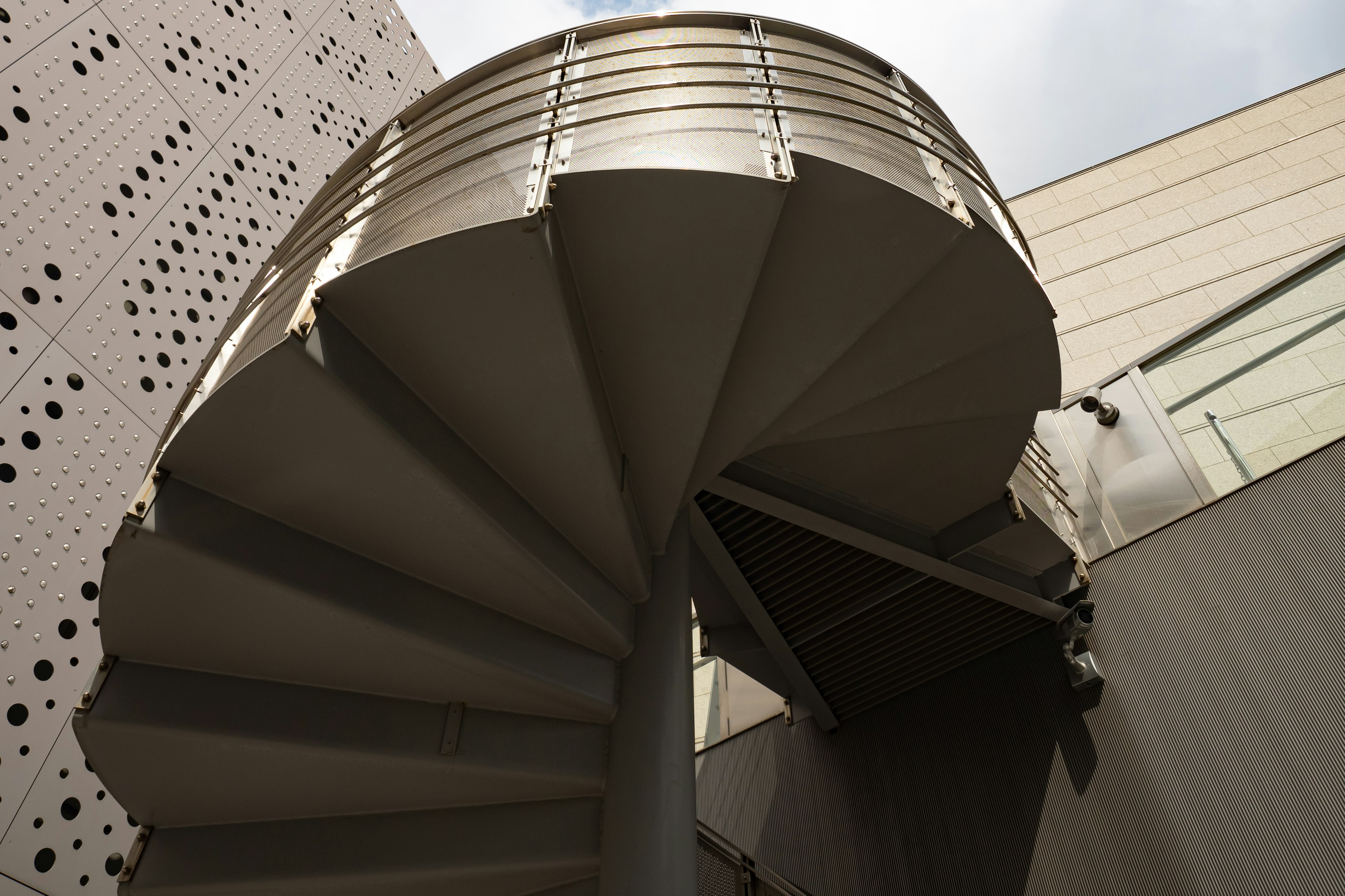 Metal spiral staircase ascending within a modern architectural setting