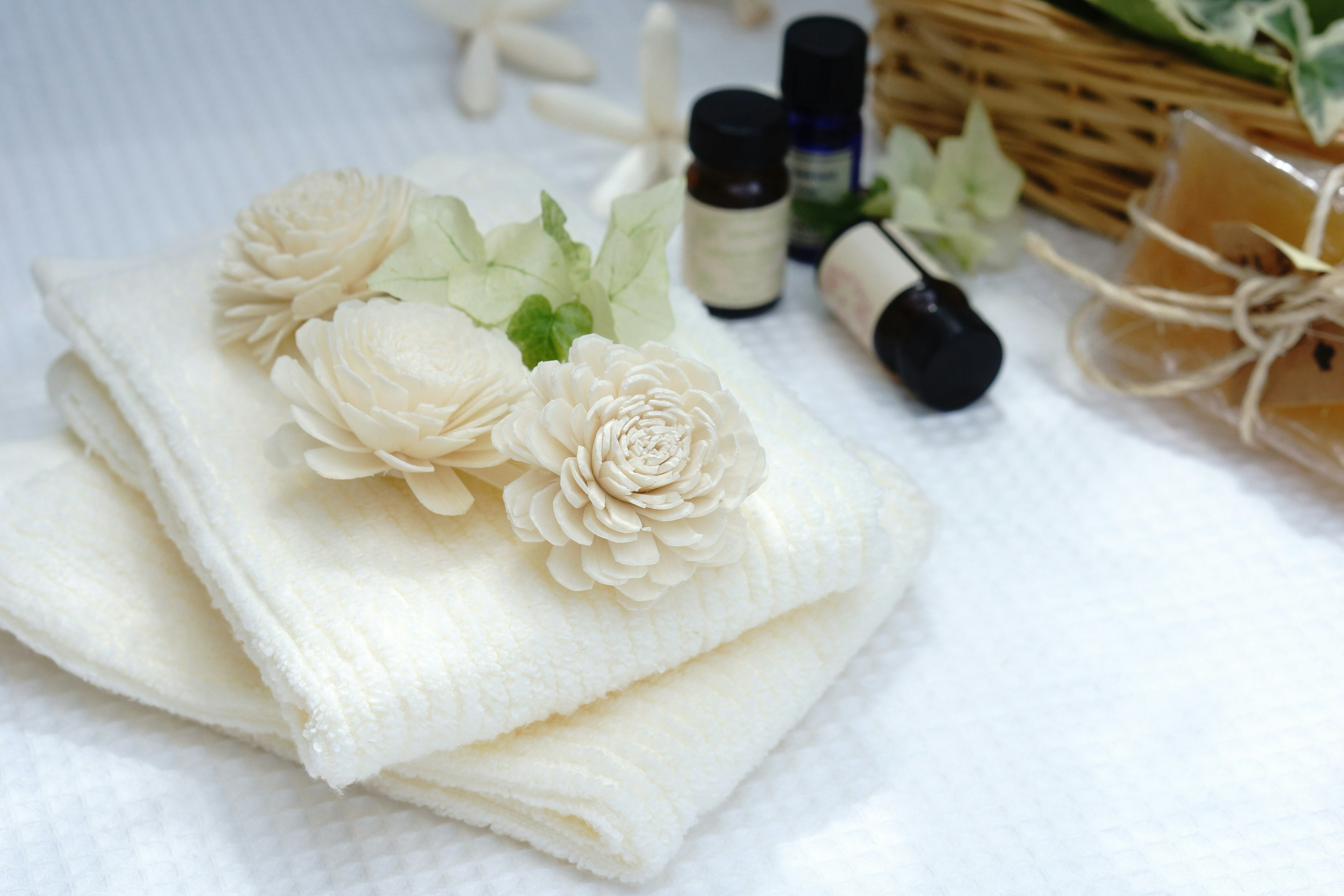 White towels adorned with cream flowers surrounded by essential oils