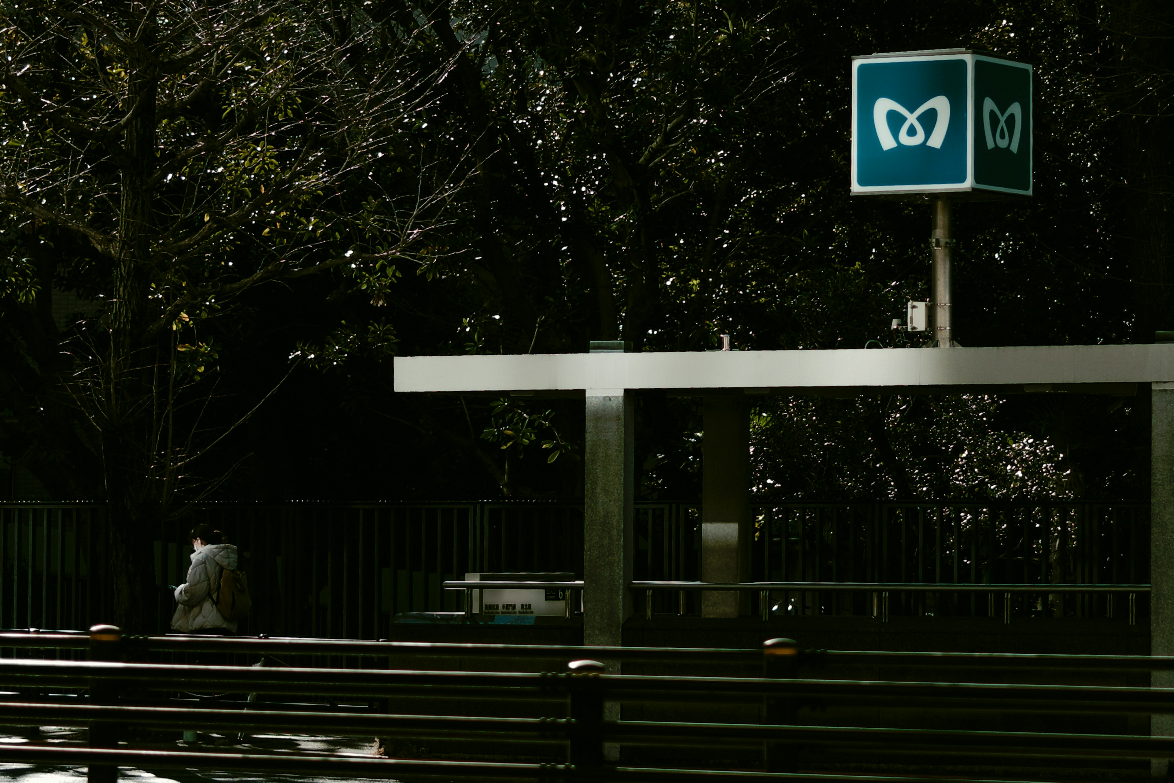 Un letrero de estación con un logo de mariposa azul rodeado de vegetación