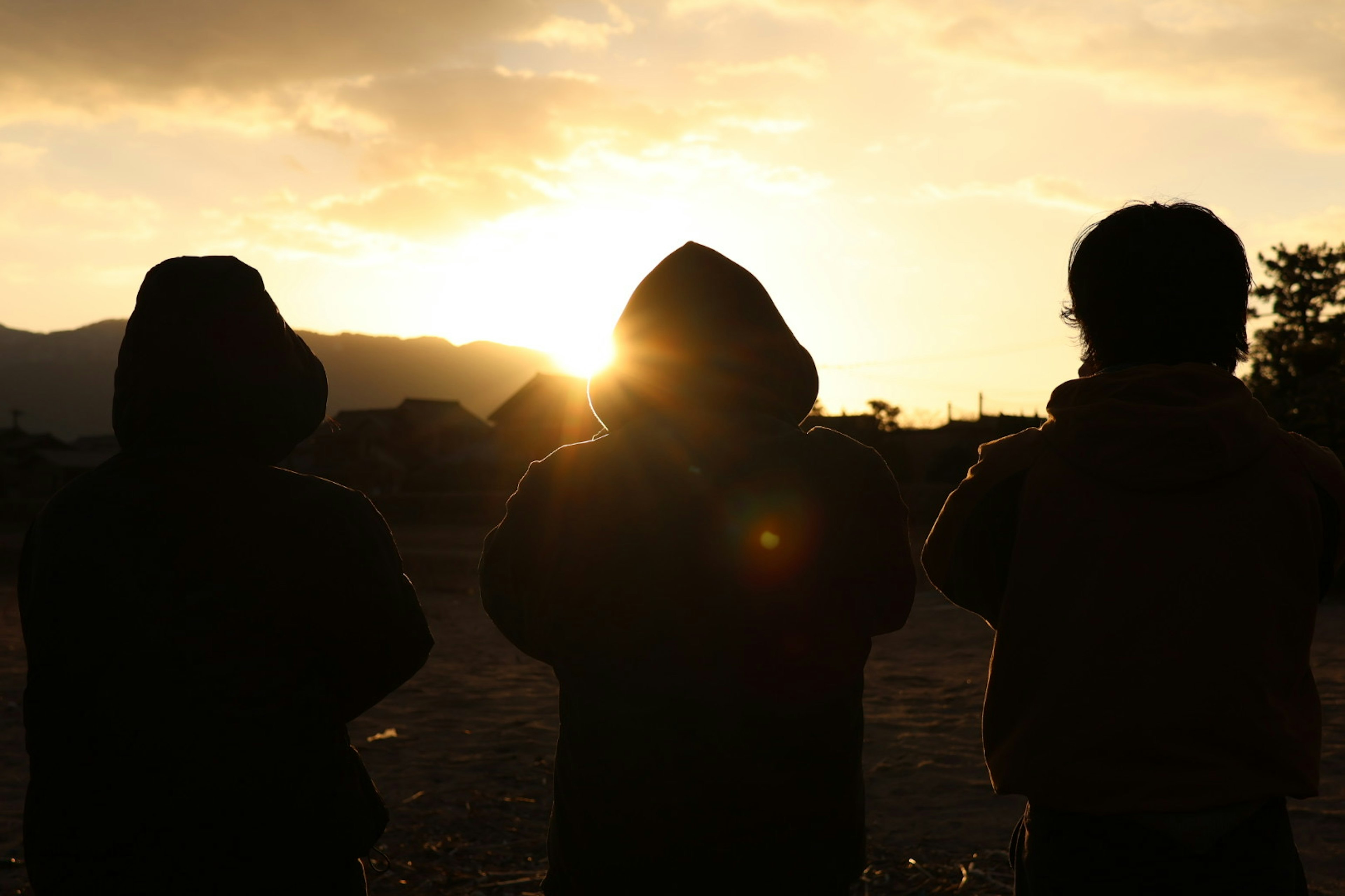 Silueta de tres personas contra un atardecer