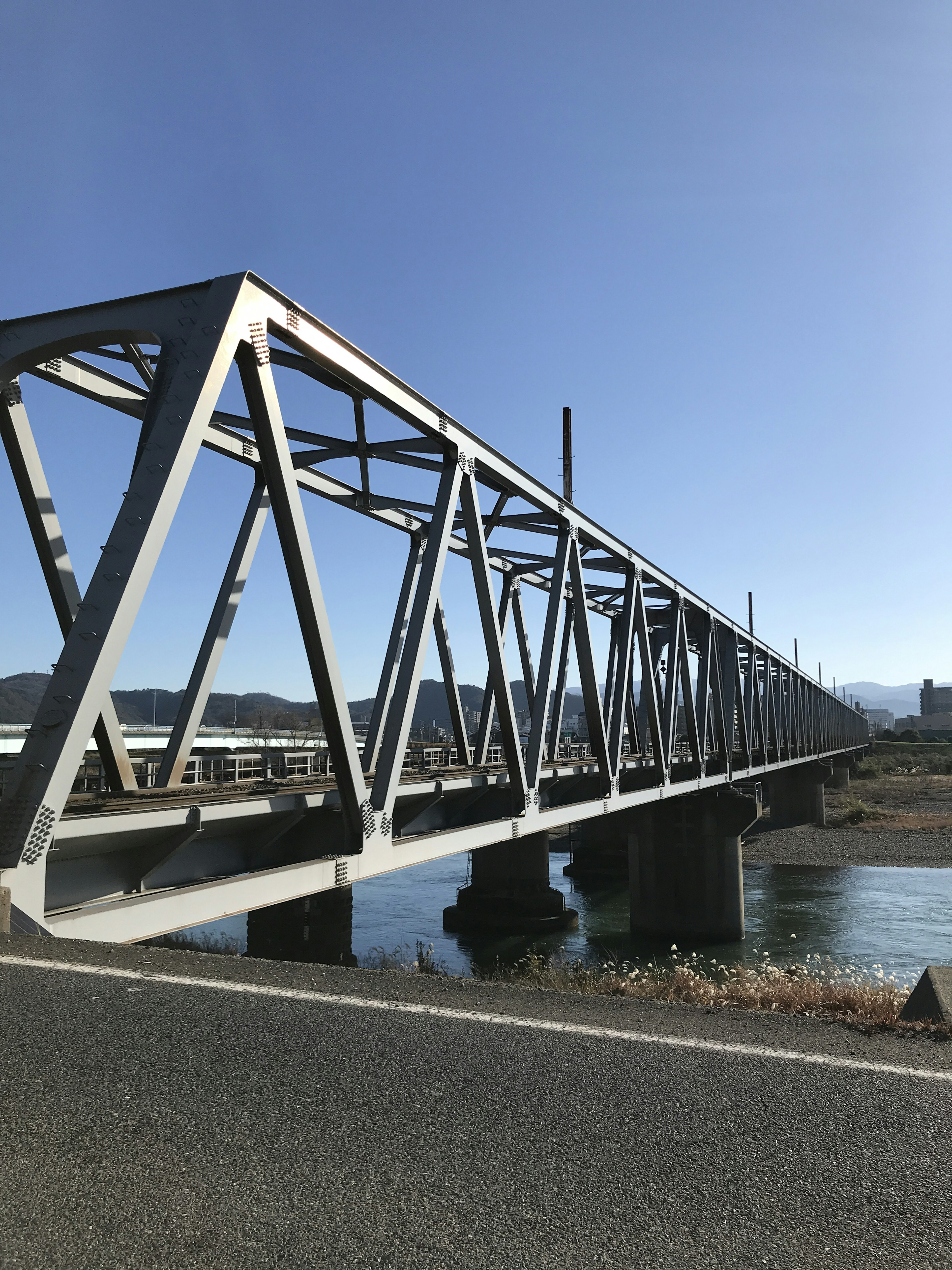 Metal truss bridge spanning over water with clear blue sky