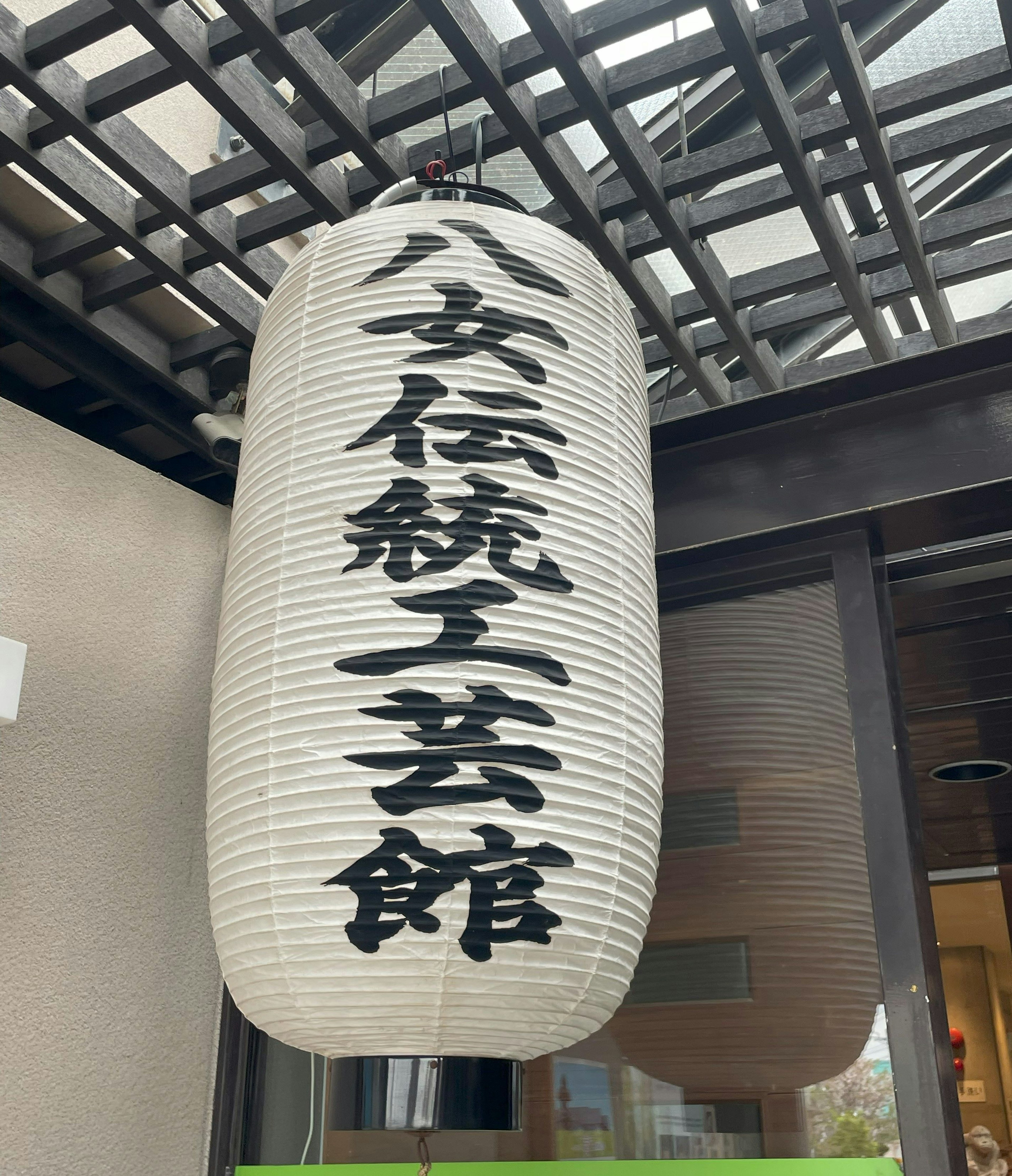 A white lantern with black characters hanging as a sign