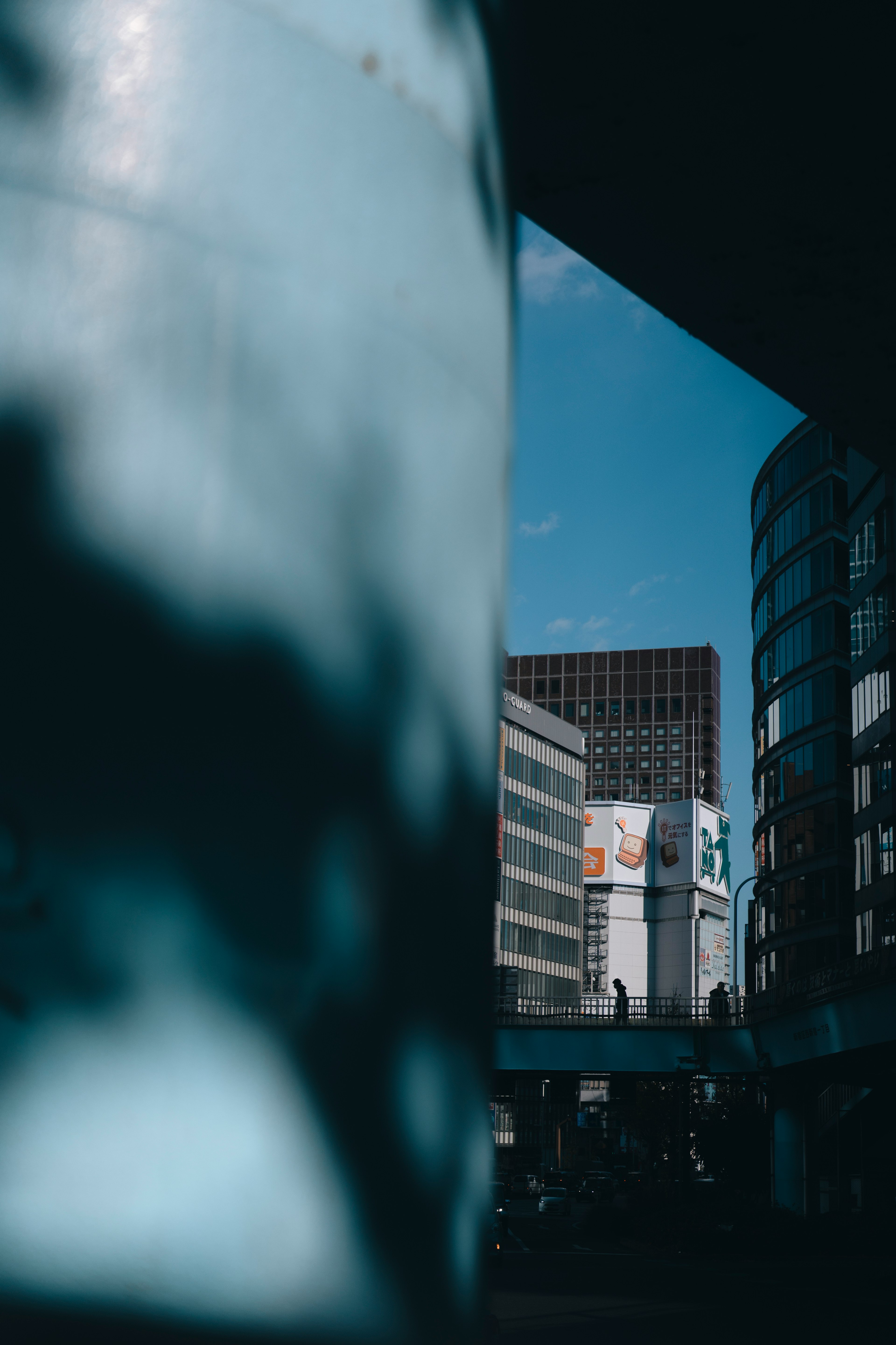 Modern buildings under a blue sky with a shadowy column