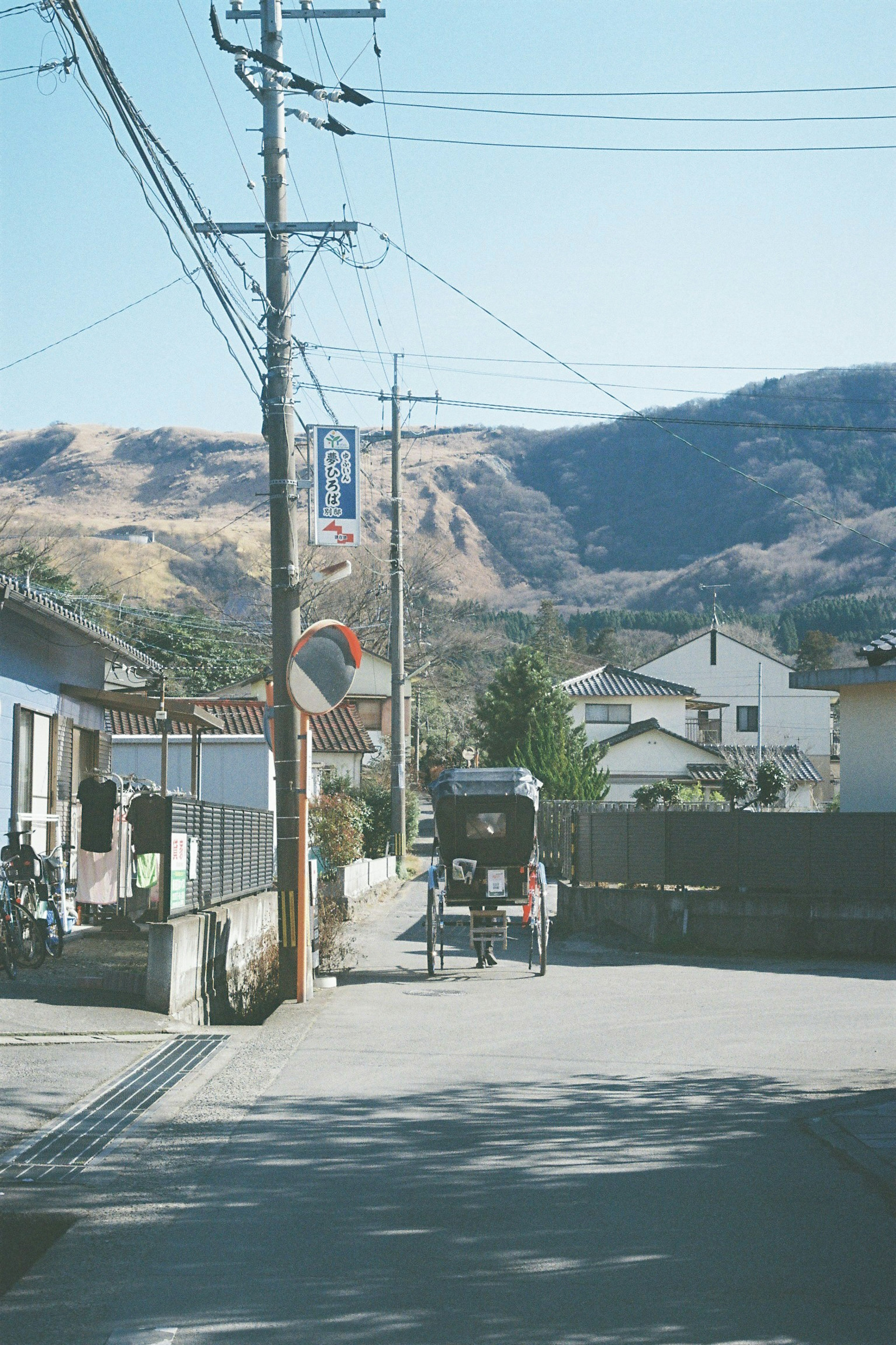 静かな日本の住宅街の風景　山々を背景にした道　電柱と家々が並ぶ