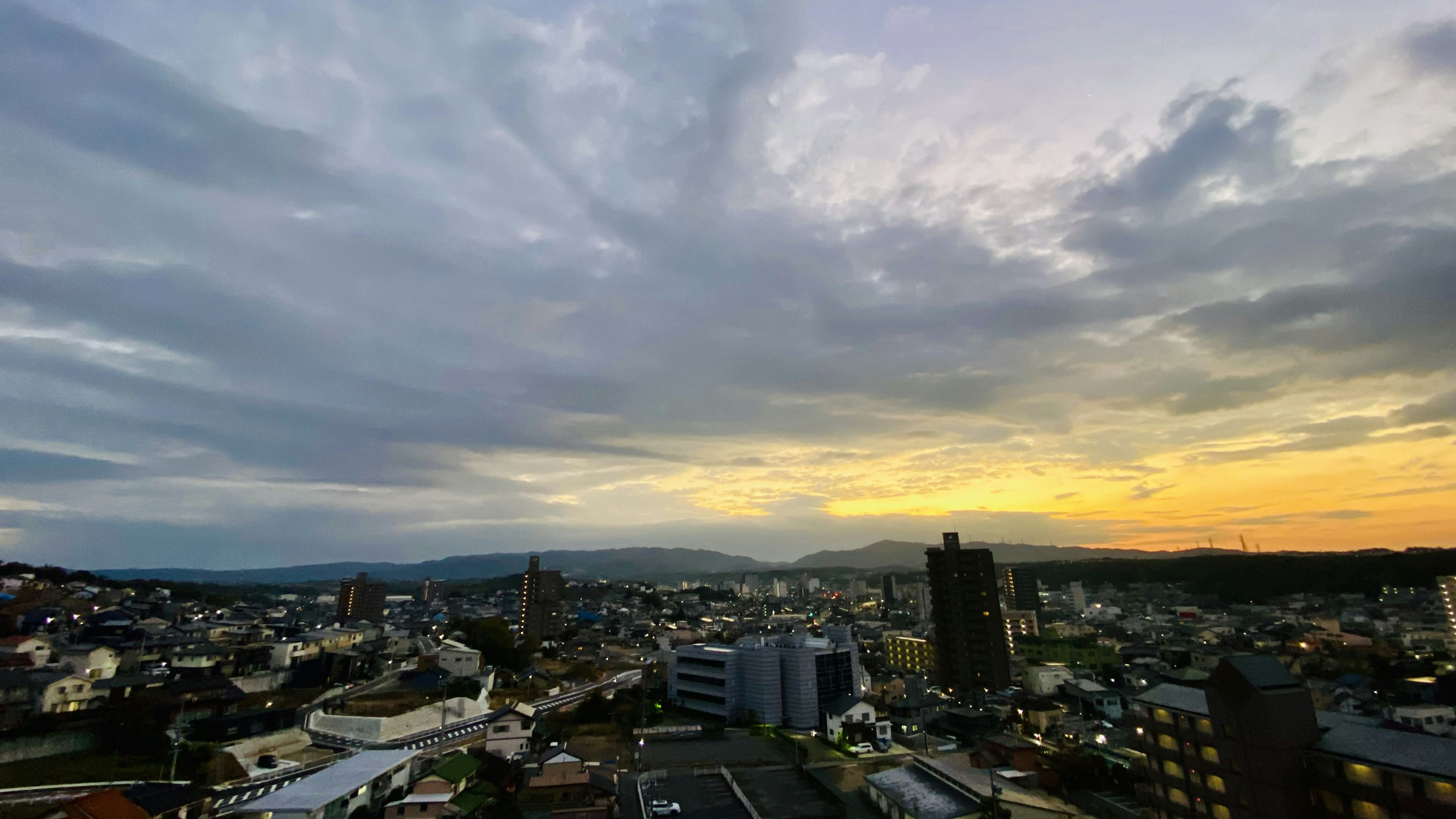 Vista panorámica de una ciudad al atardecer con edificios altos y áreas residenciales