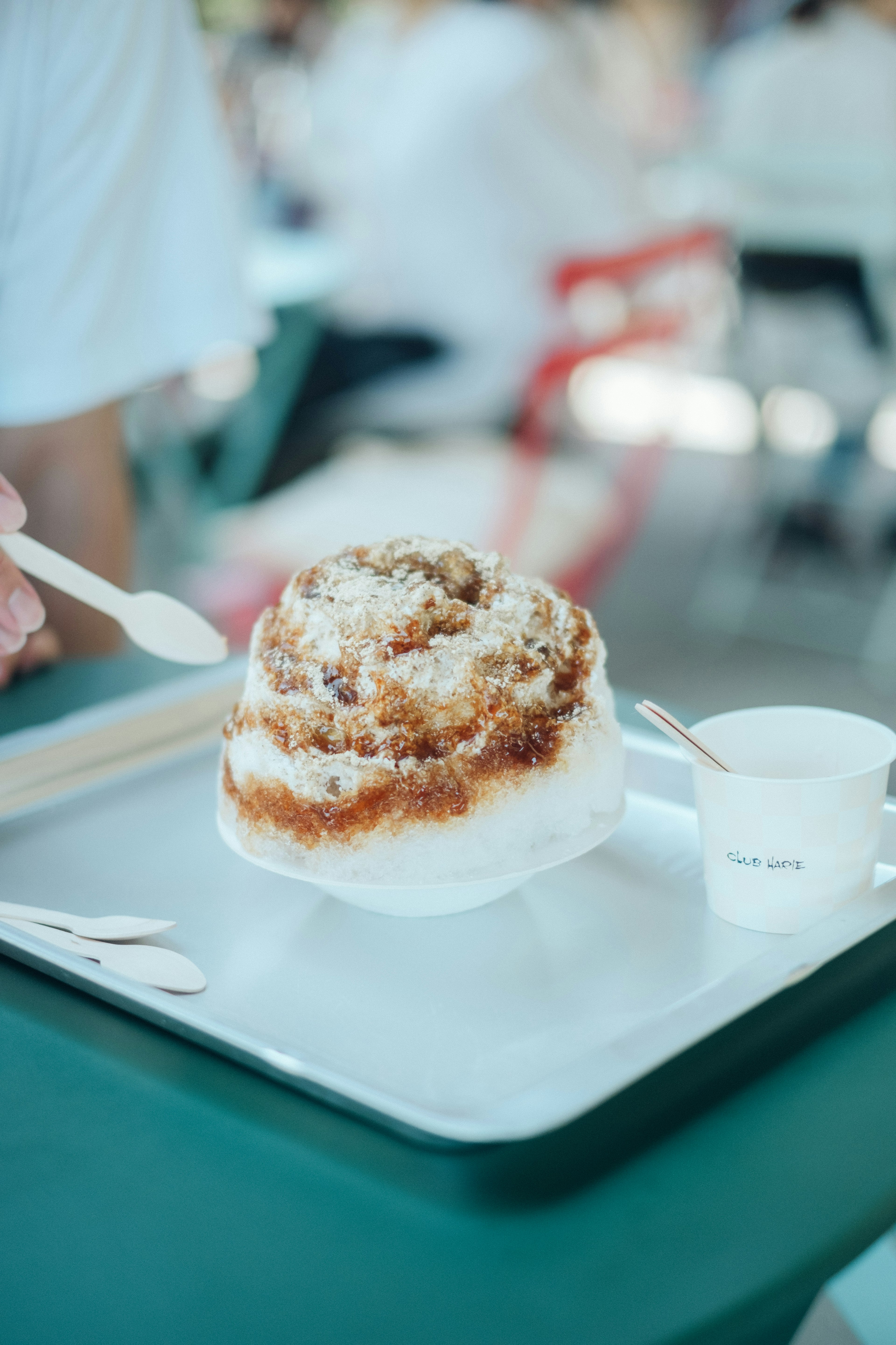 Eine Hand, die einen Löffel mit einem süßen Dessert auf einem Tablett hält