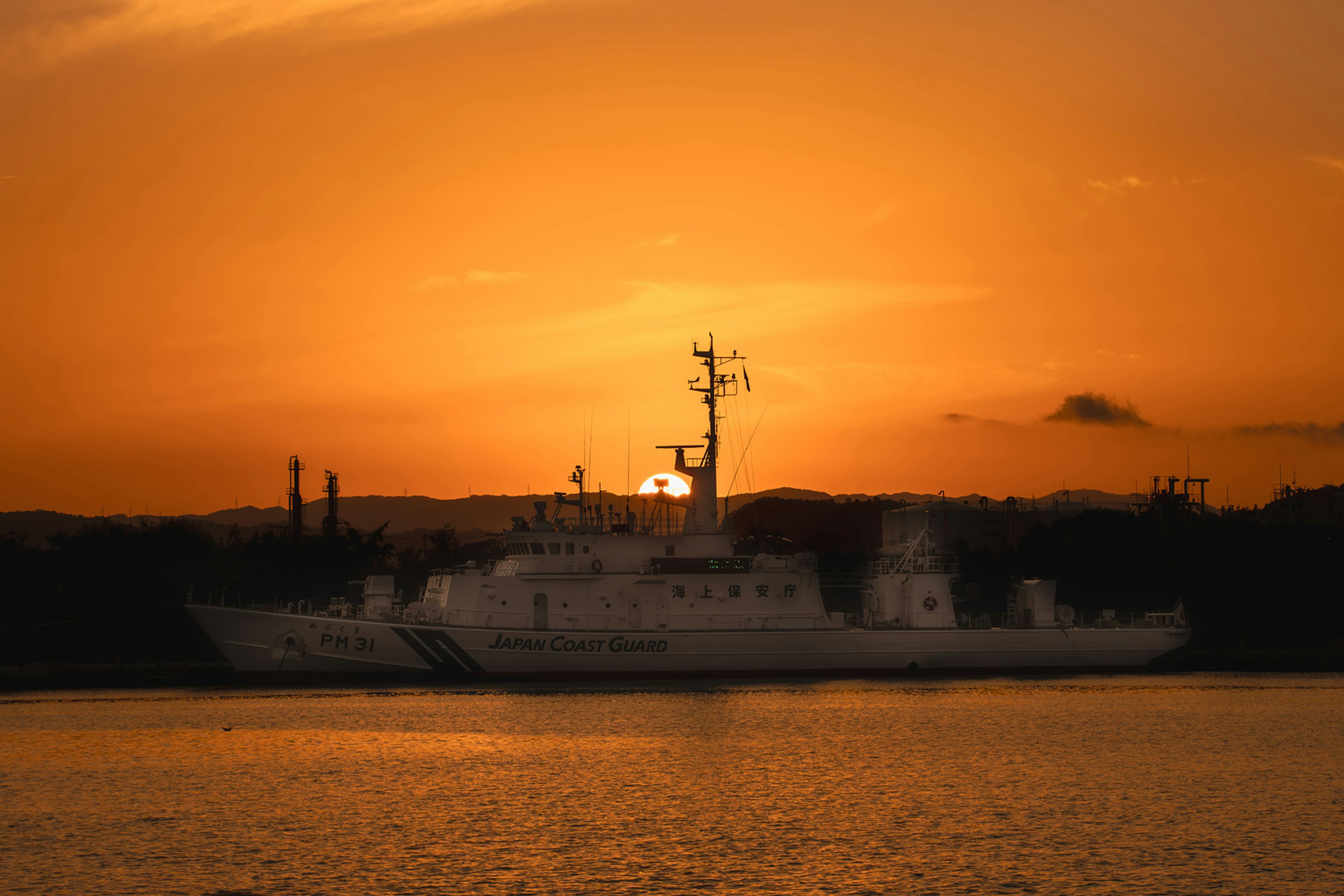 夕日を背景にした白い船が水面に浮かんでいる風景