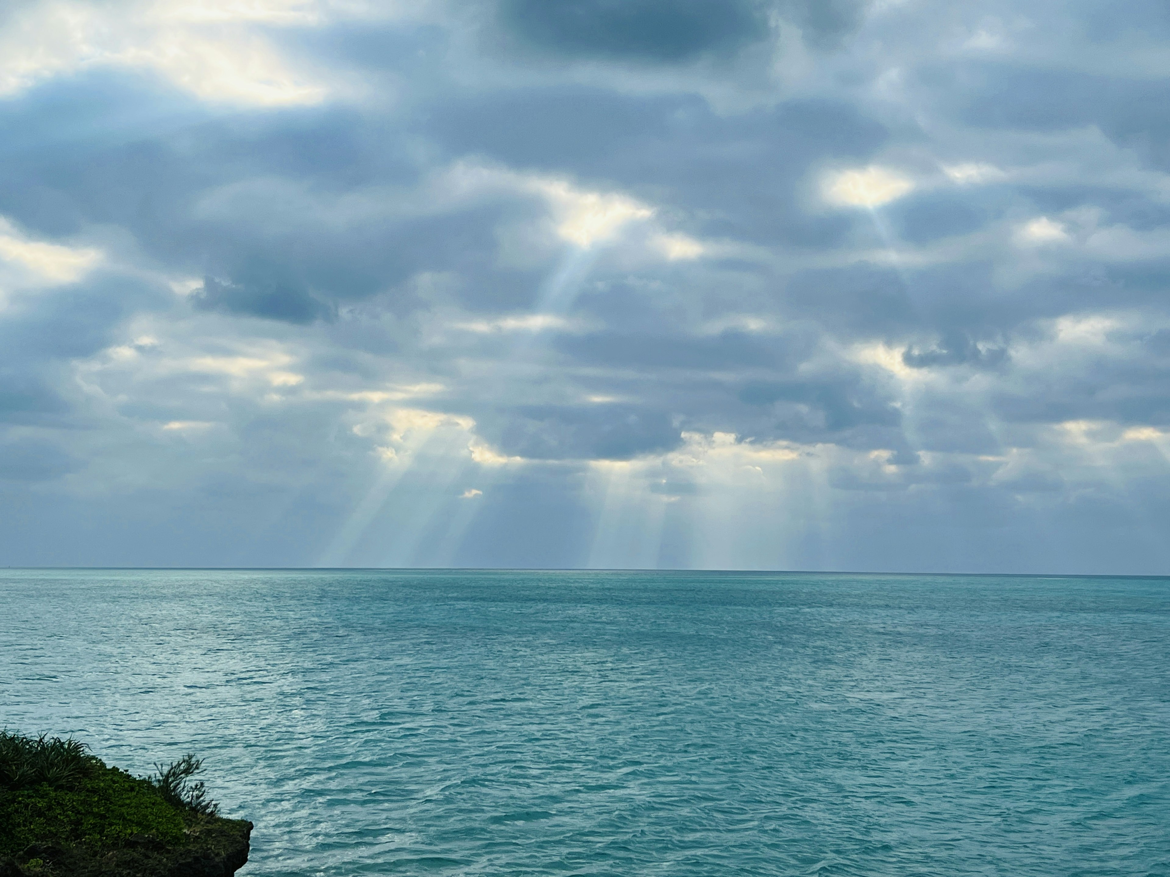 寧靜的海景帶有多雲的天空和碧綠色的水陽光透過雲層