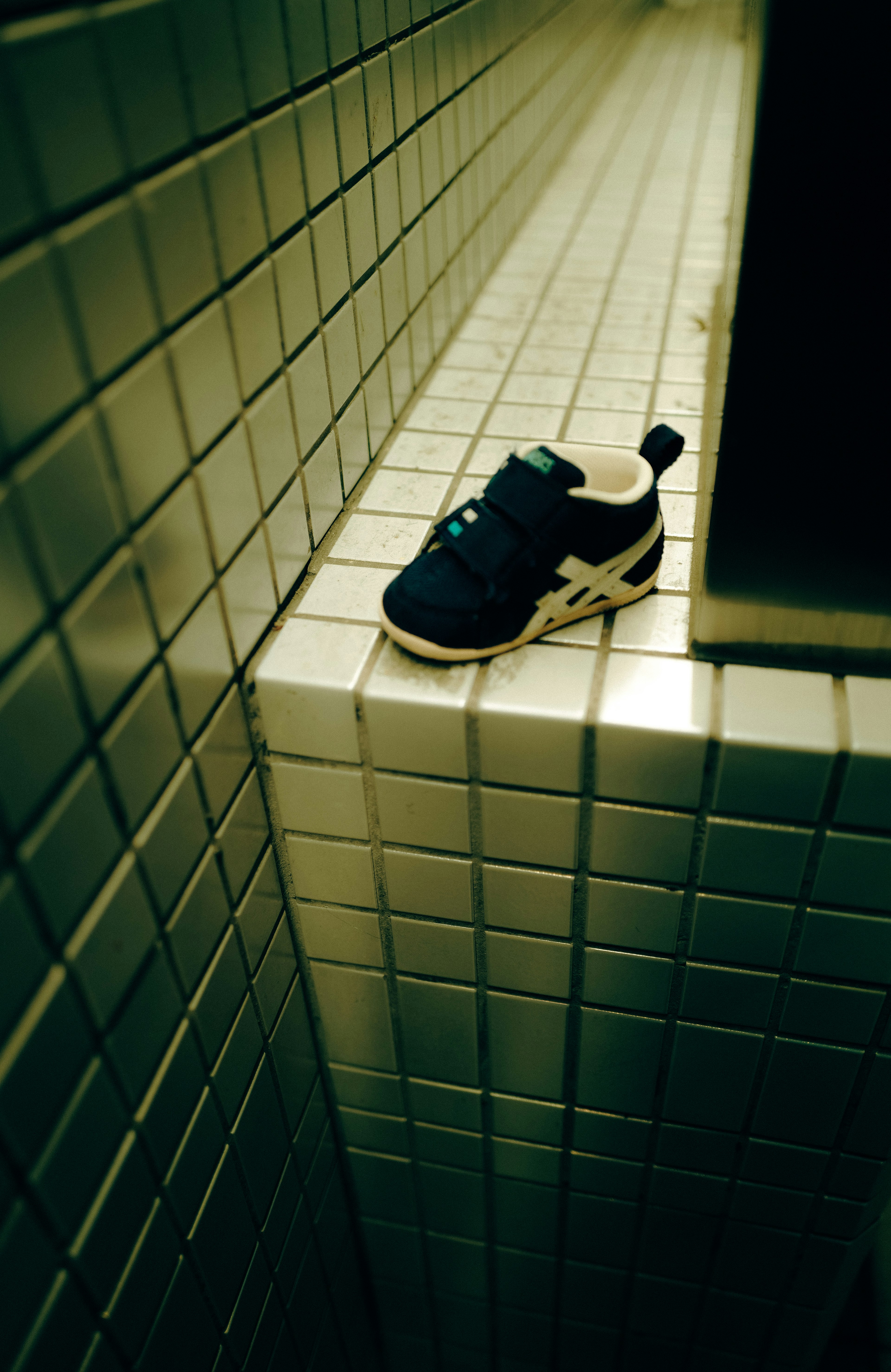 Une sneaker bleue posée sur un rebord carrelé