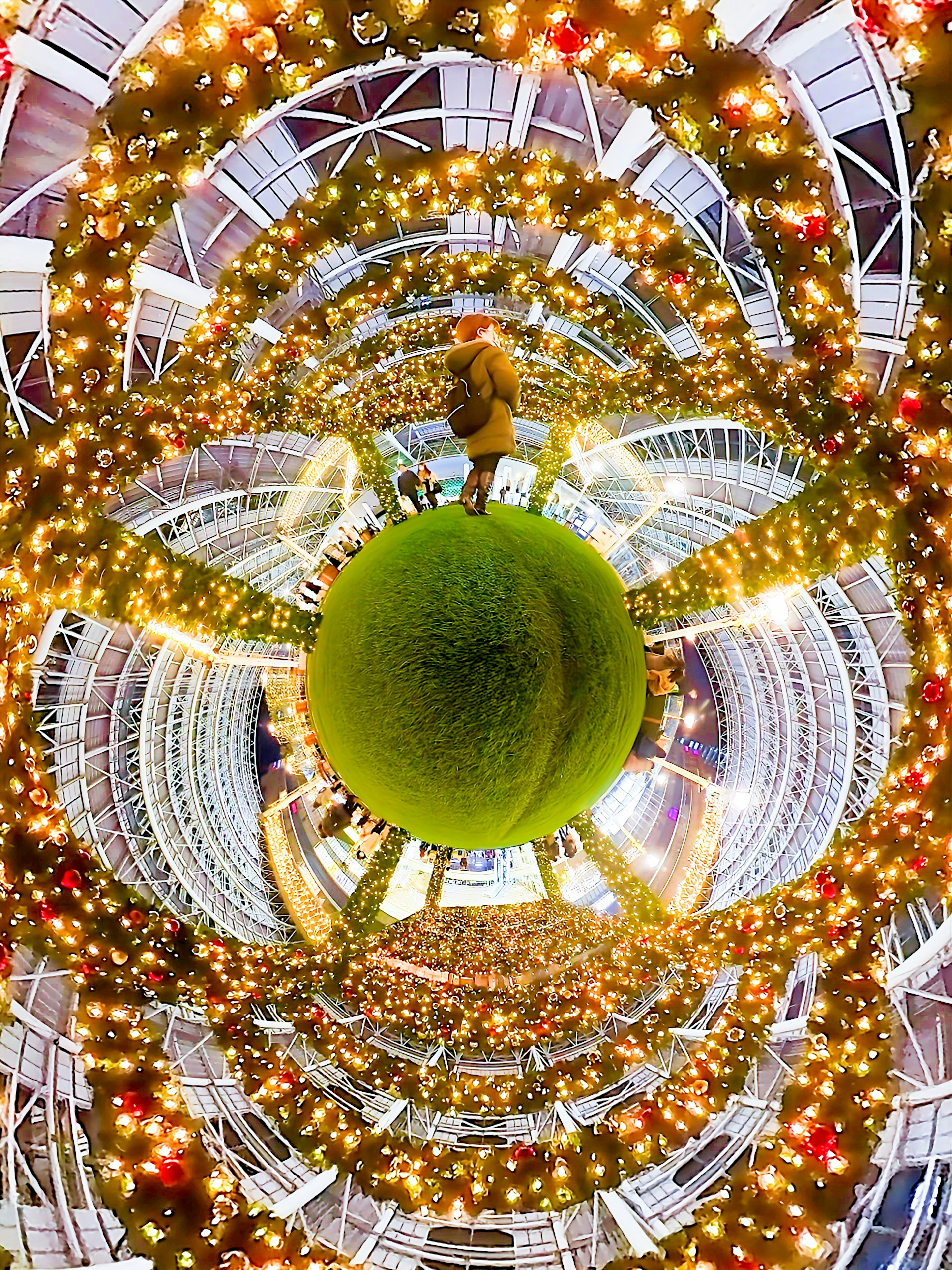 Person standing on a green sphere surrounded by circular light decorations