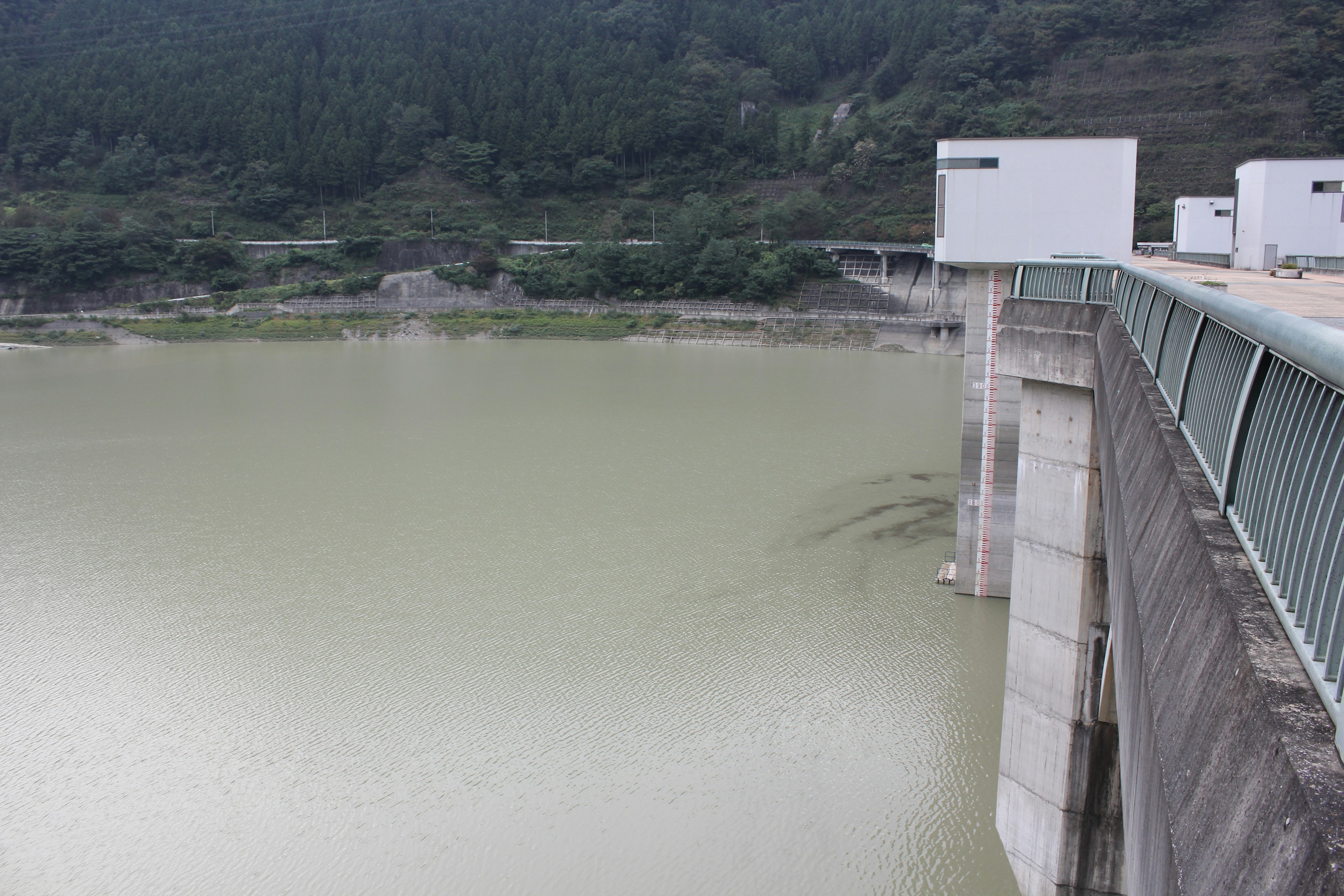 View of a dam with a muddy water surface and surrounding mountains