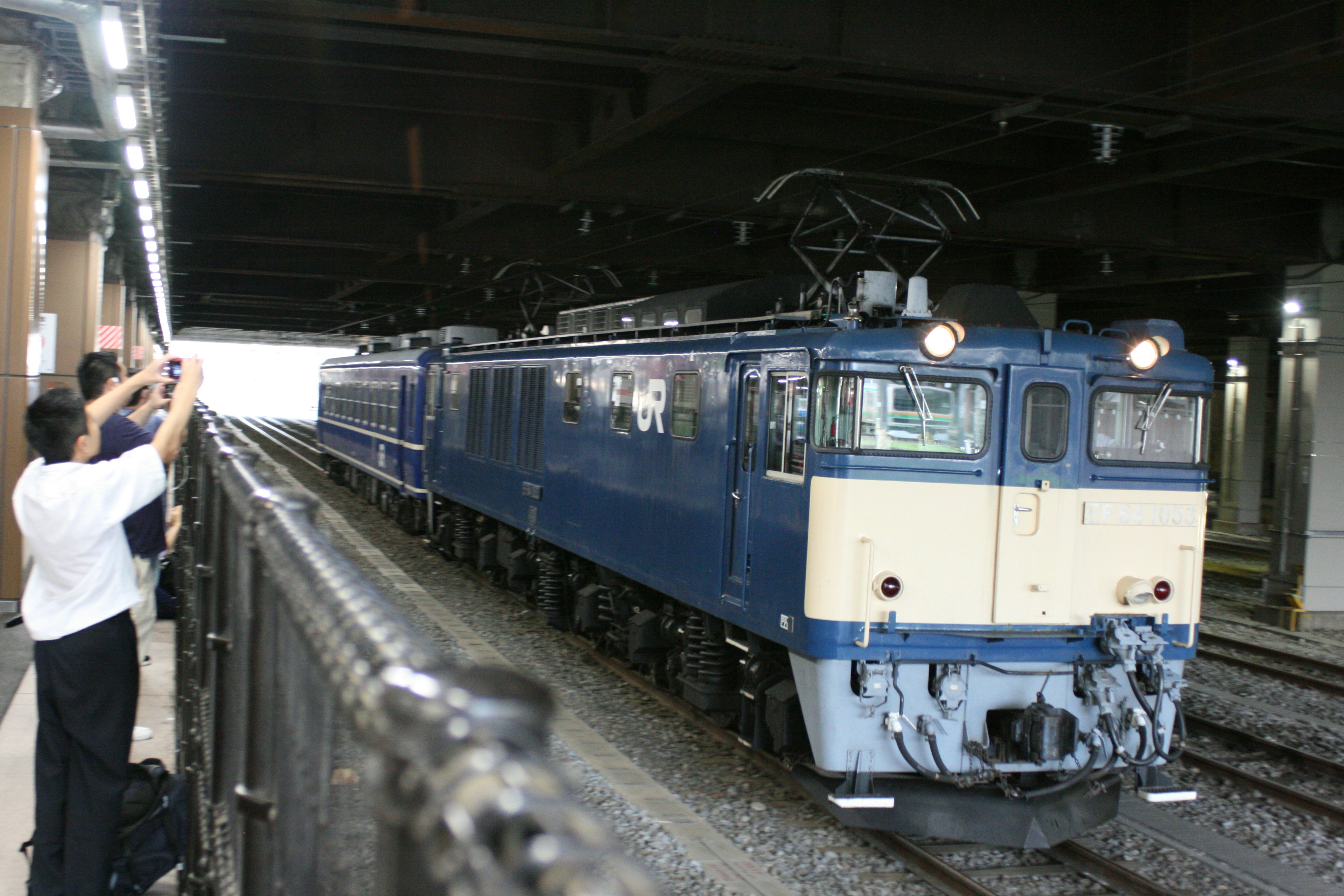 Blue electric locomotive at a station with people taking photos