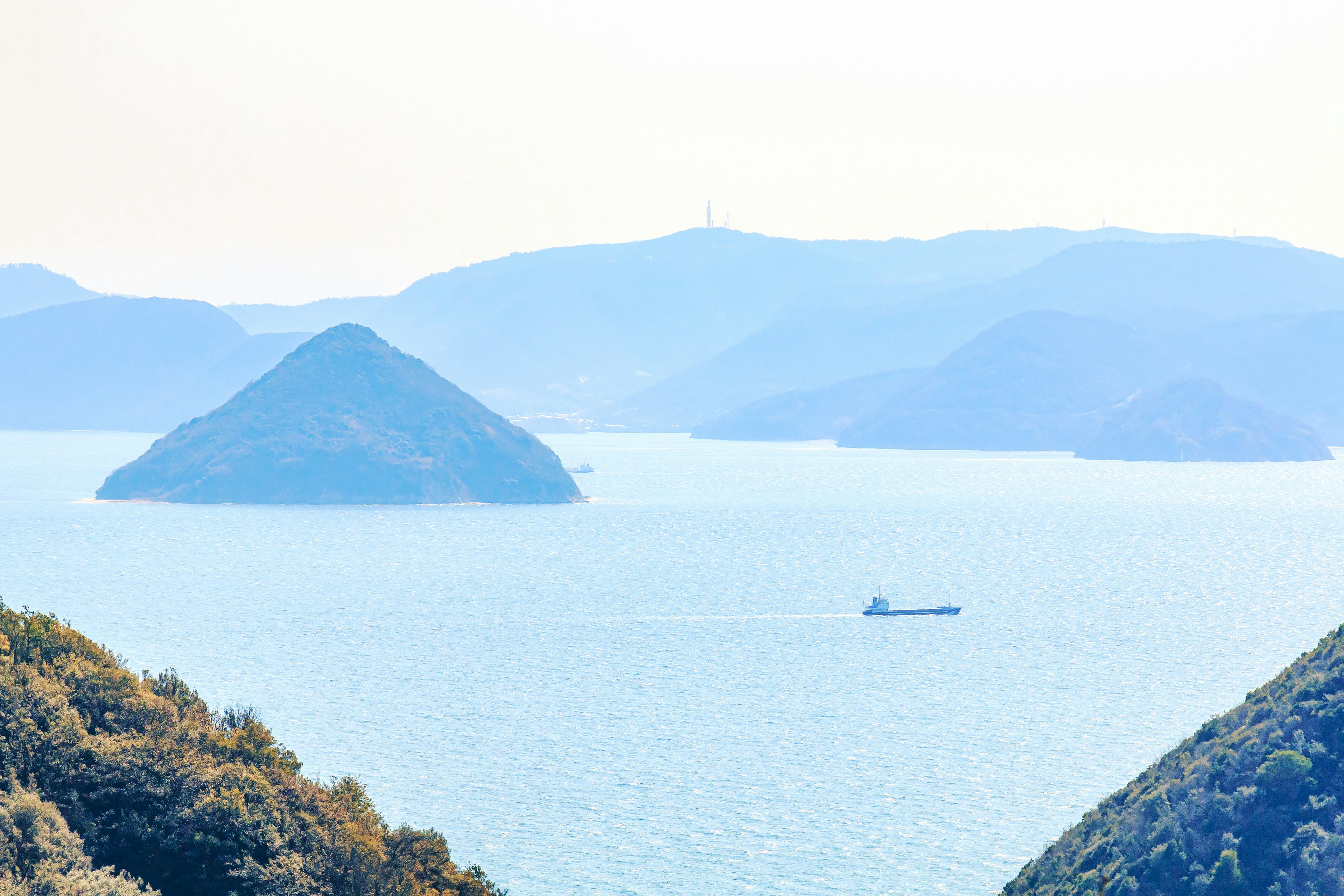 A serene landscape featuring blue sea and silhouetted mountains with a small boat floating