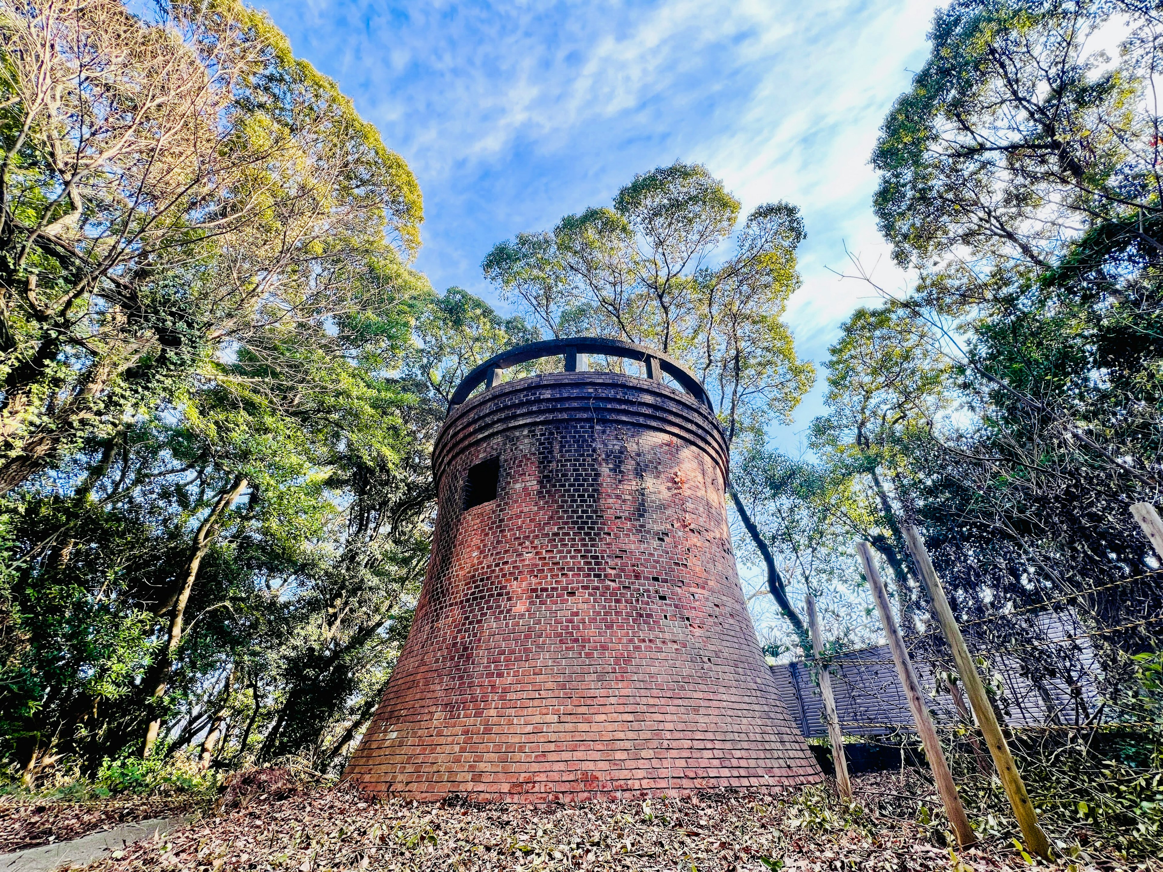 Alte Backsteinturm umgeben von Wald und blauem Himmel