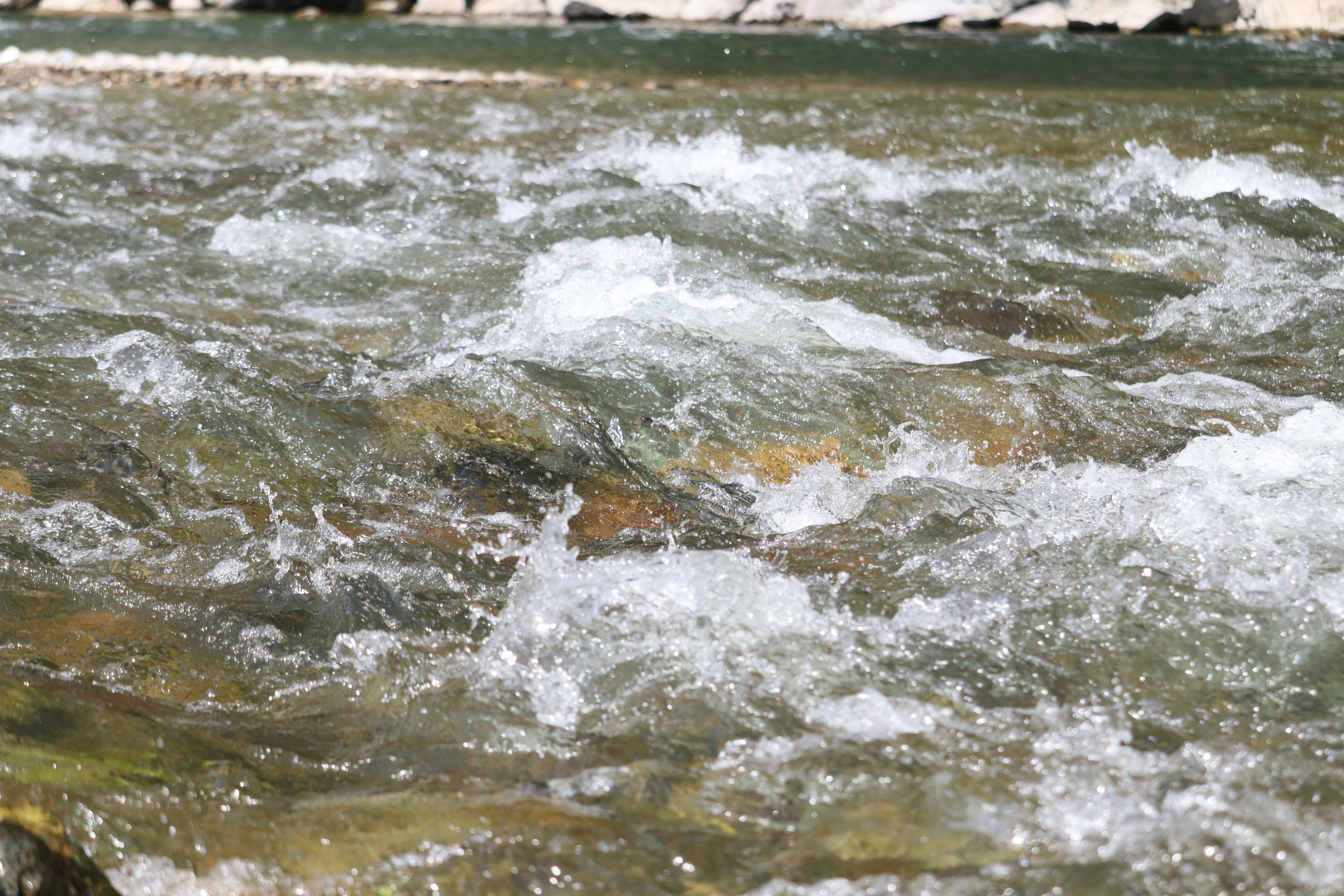 Image of flowing water with visible rocks and bubbles