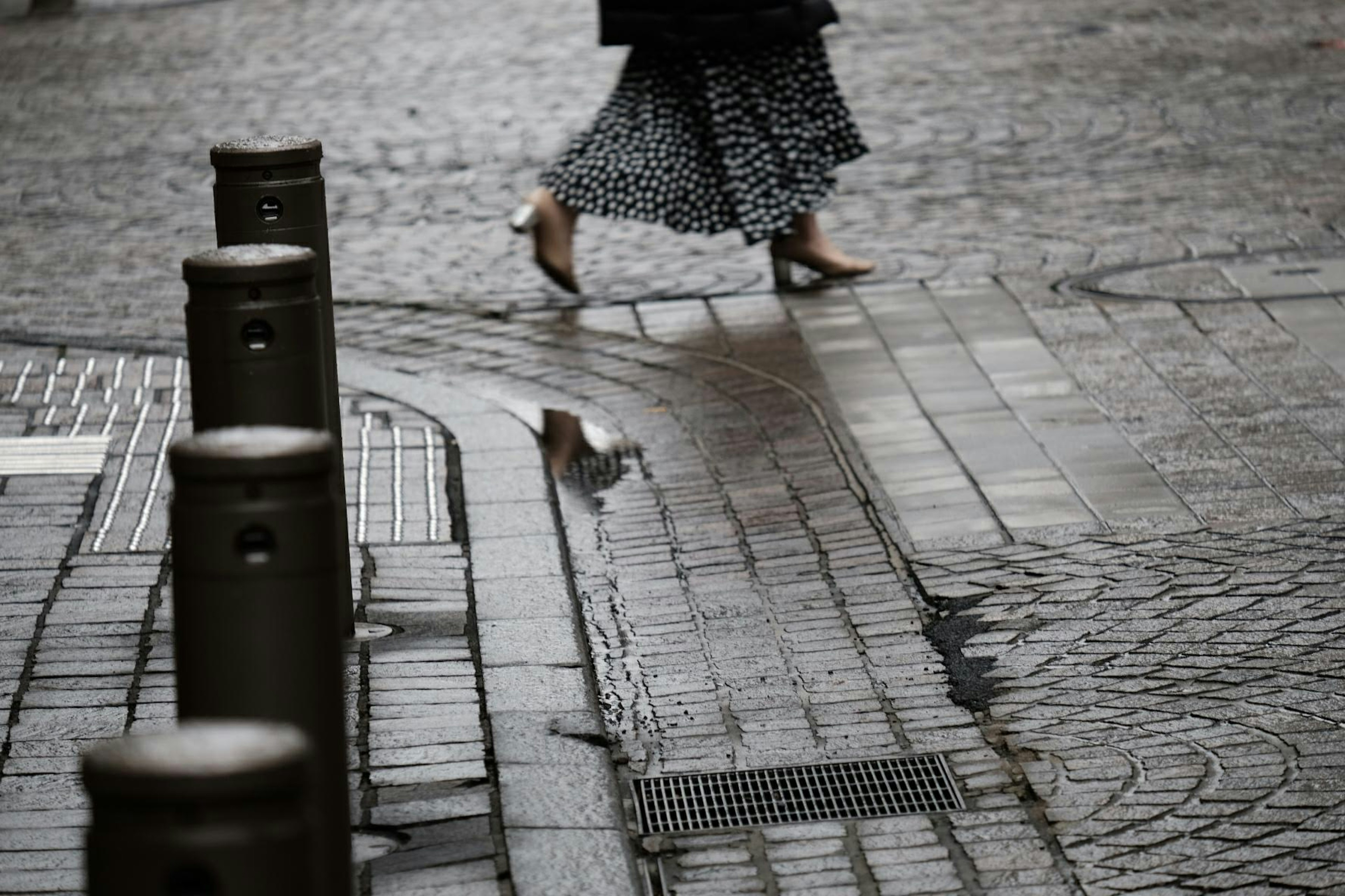 雨に濡れた石畳を歩く女性の足元と反射