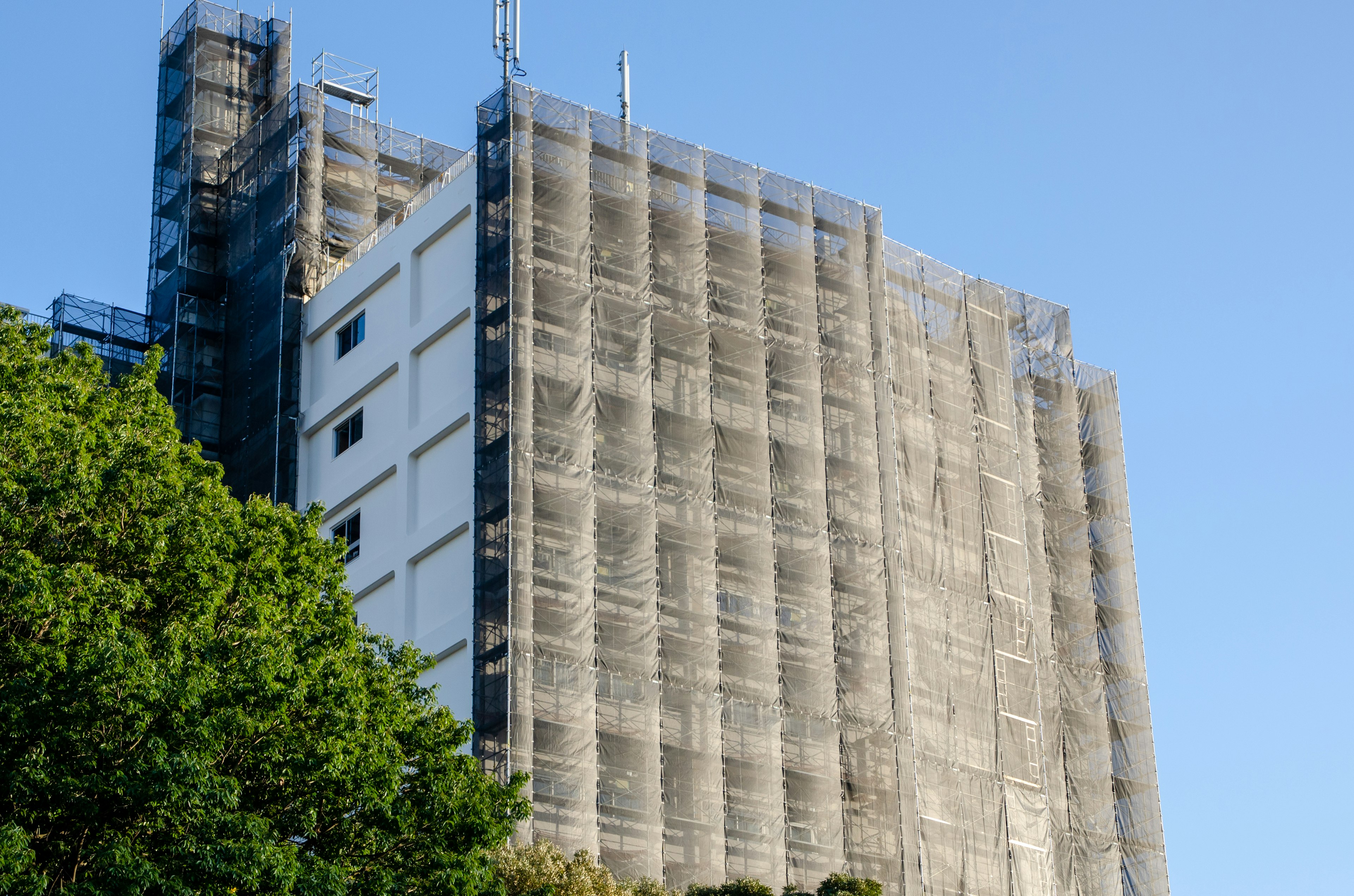 Hochhaus im Umbau mit Gerüsten und klarem blauen Himmel