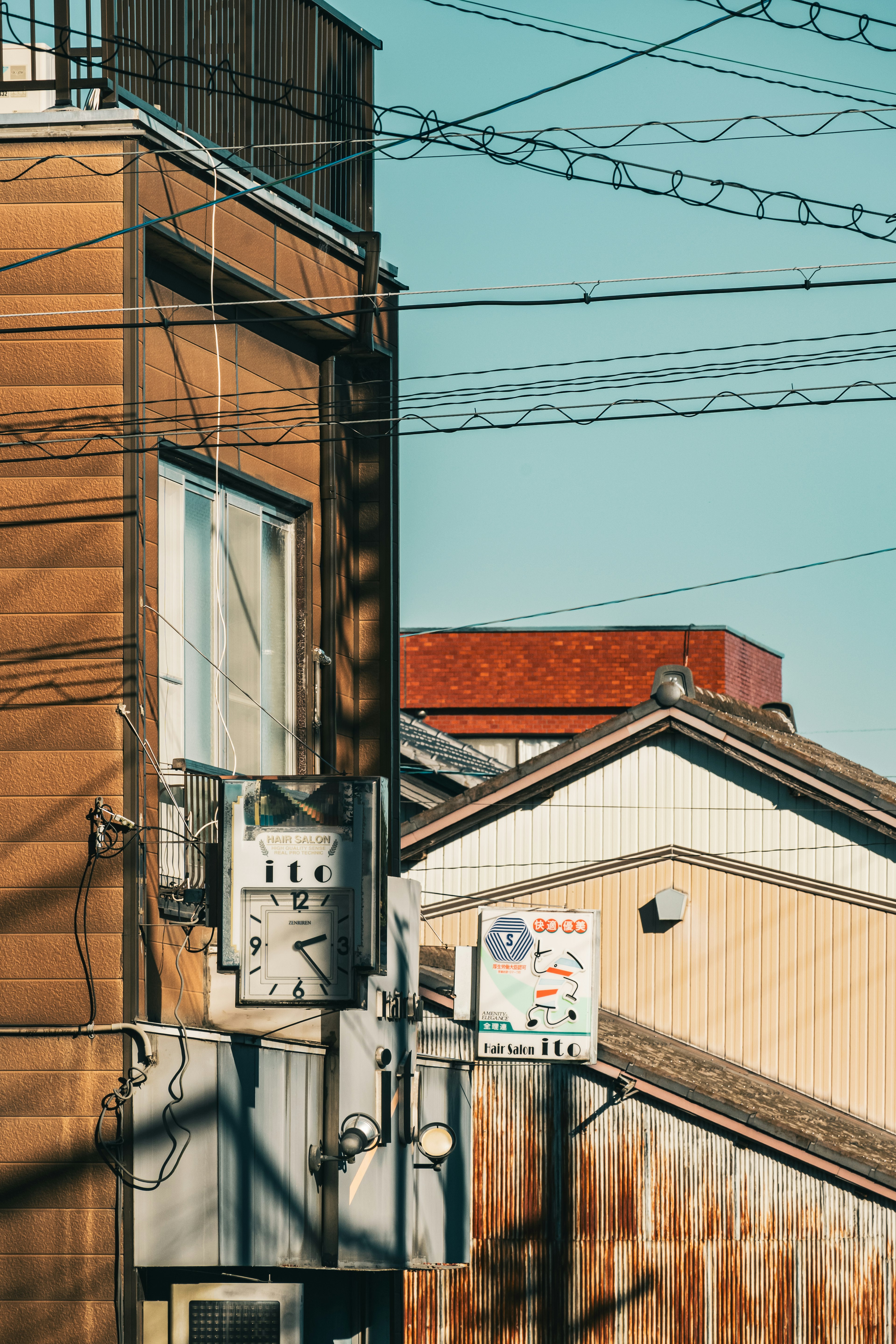 Urban scene with intersecting power lines wooden walls and windows visible red roof house in the background