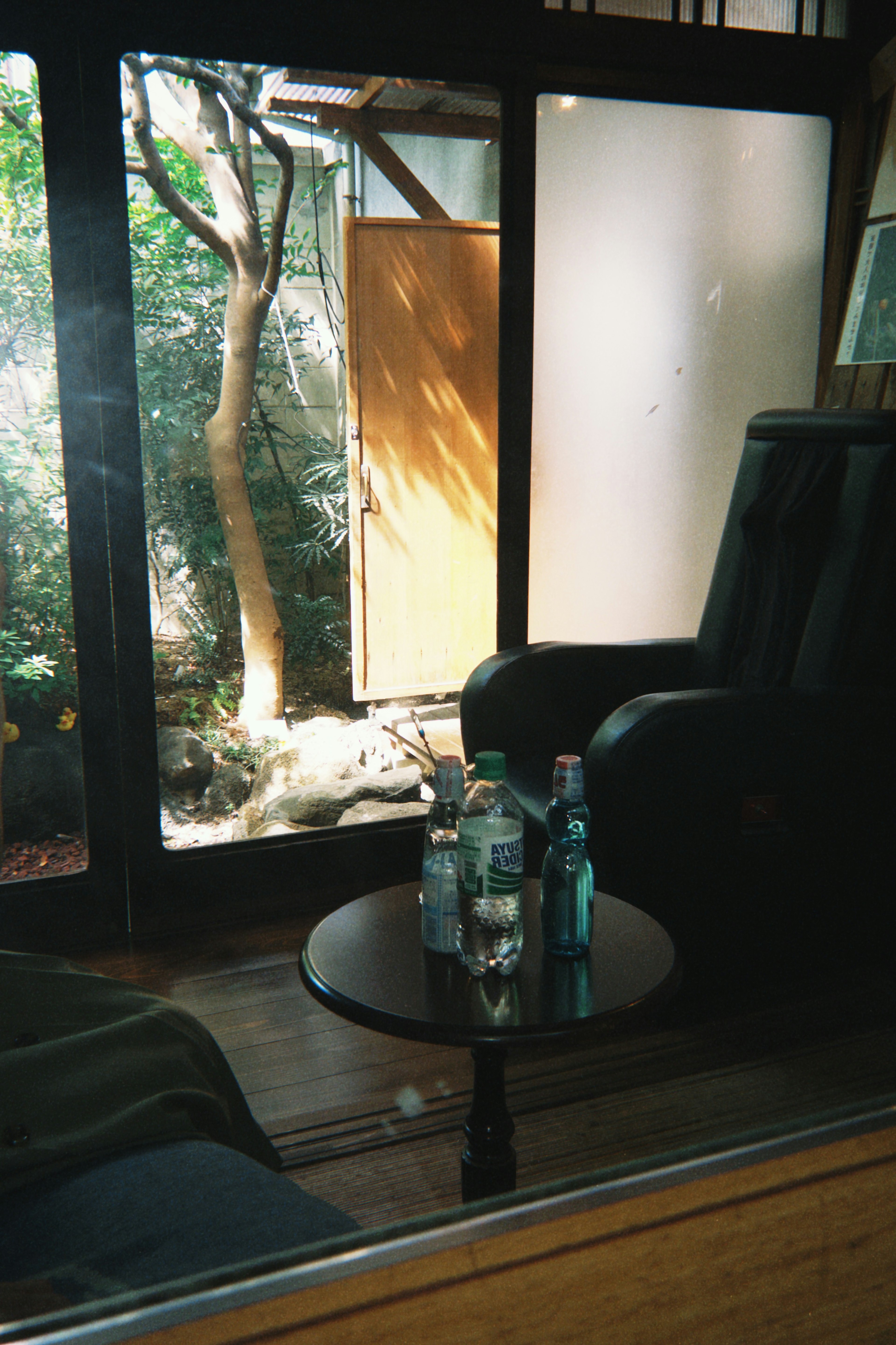 Vue d'un jardin à travers une porte en verre avec un panneau en bois et une table basse