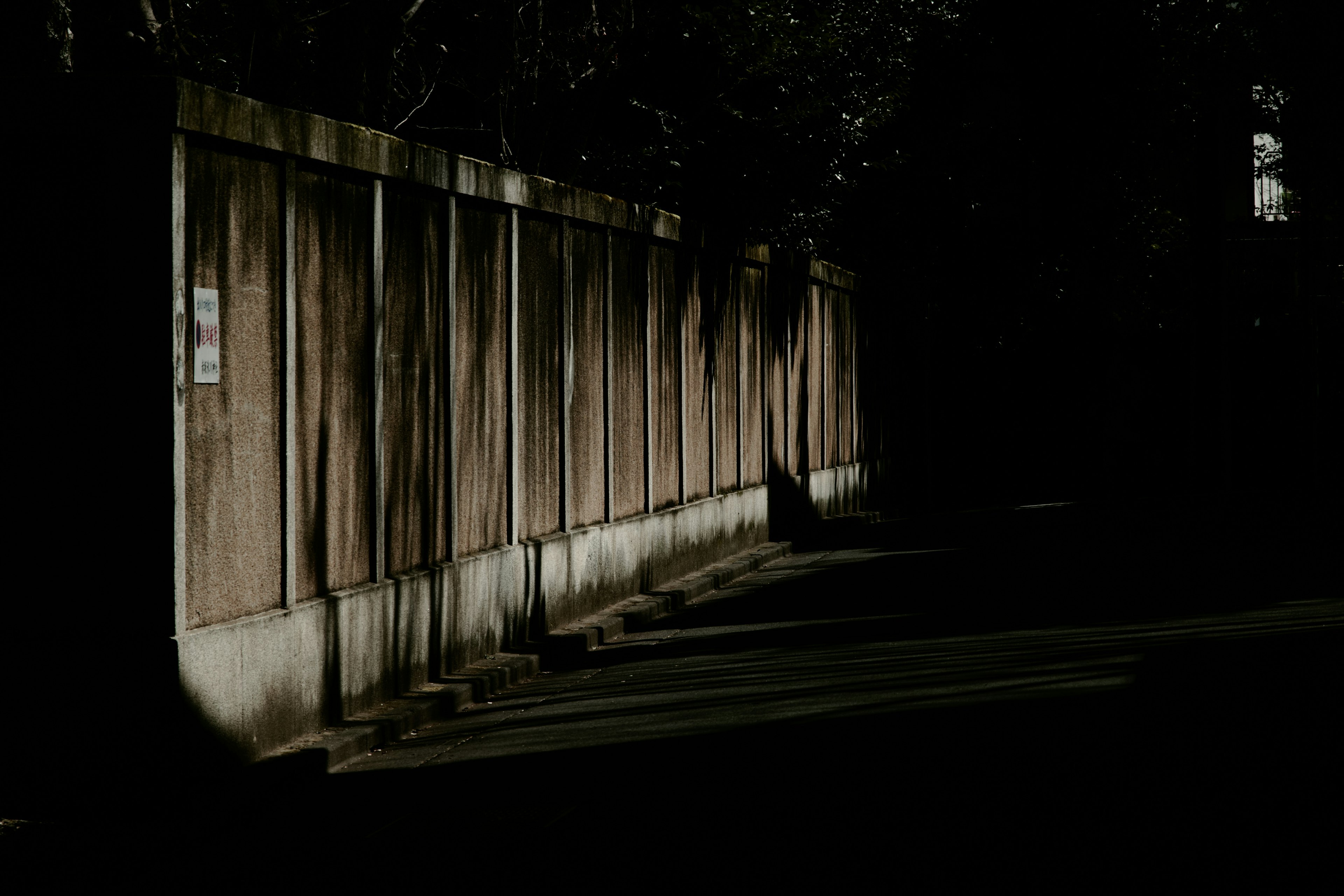 Sombra de una cerca de madera a lo largo de una calle oscura