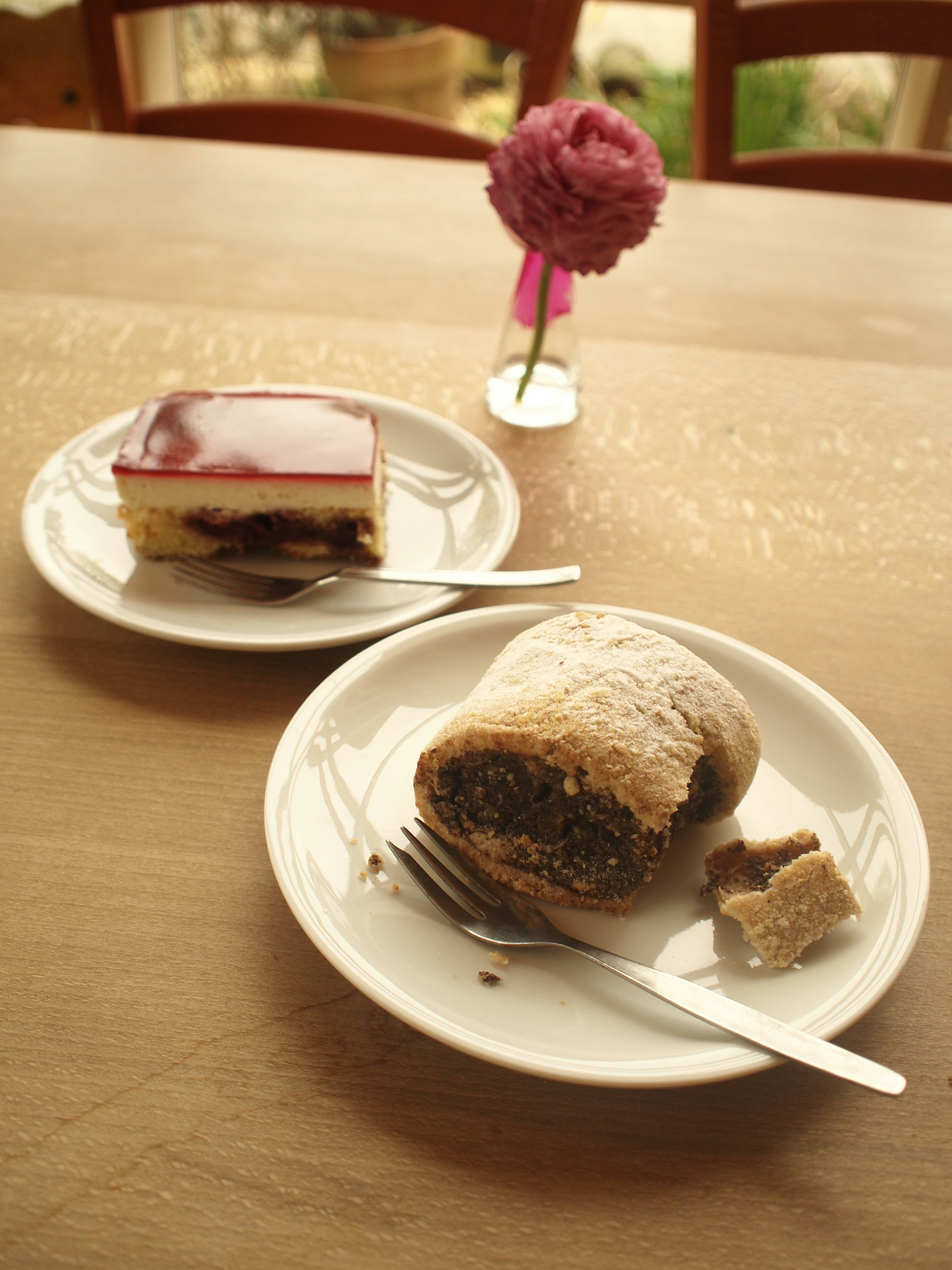 Deux desserts sur des assiettes avec un petit vase à fleurs sur la table