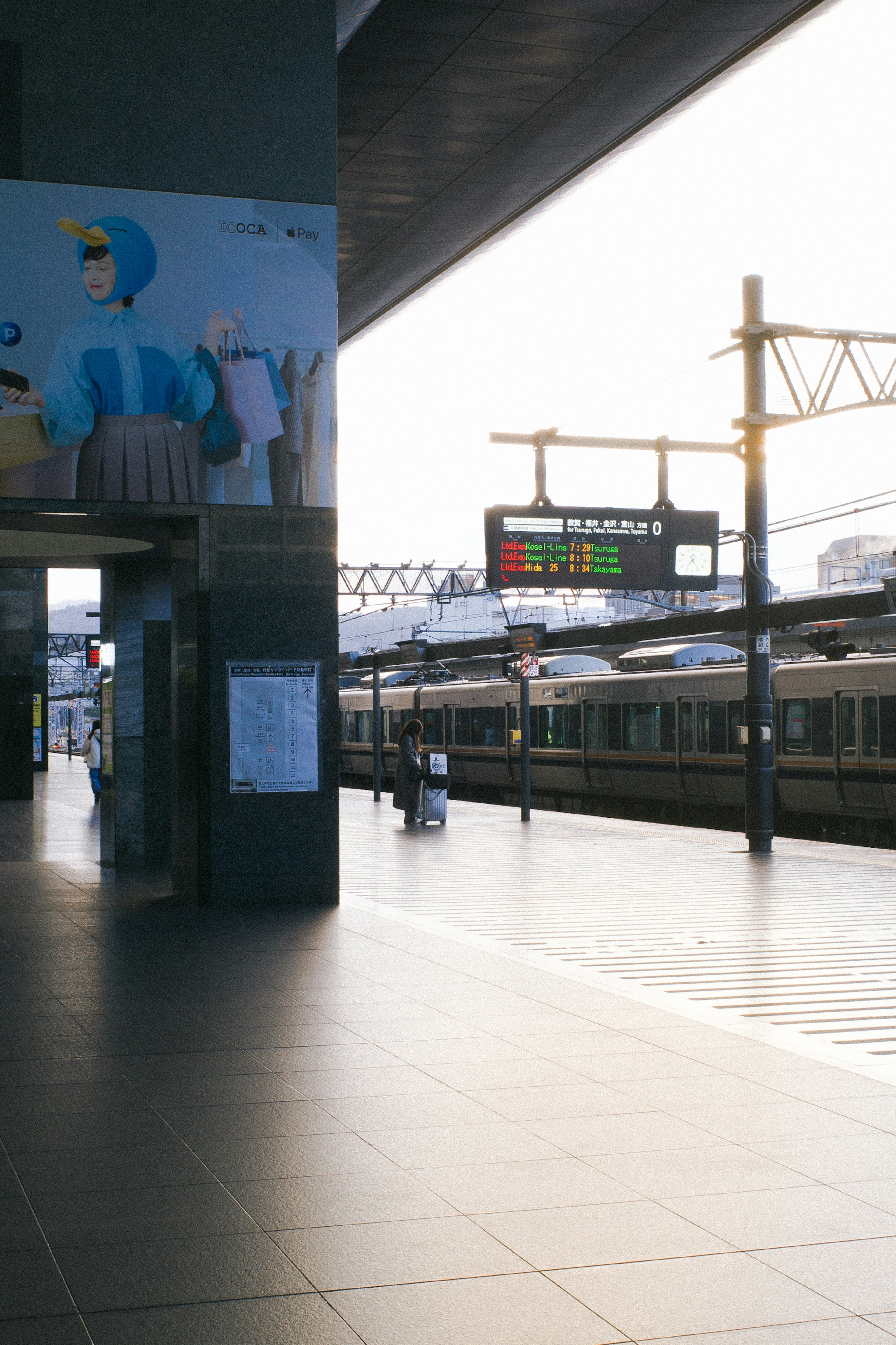 Train station platform with visible trains and colorful signage