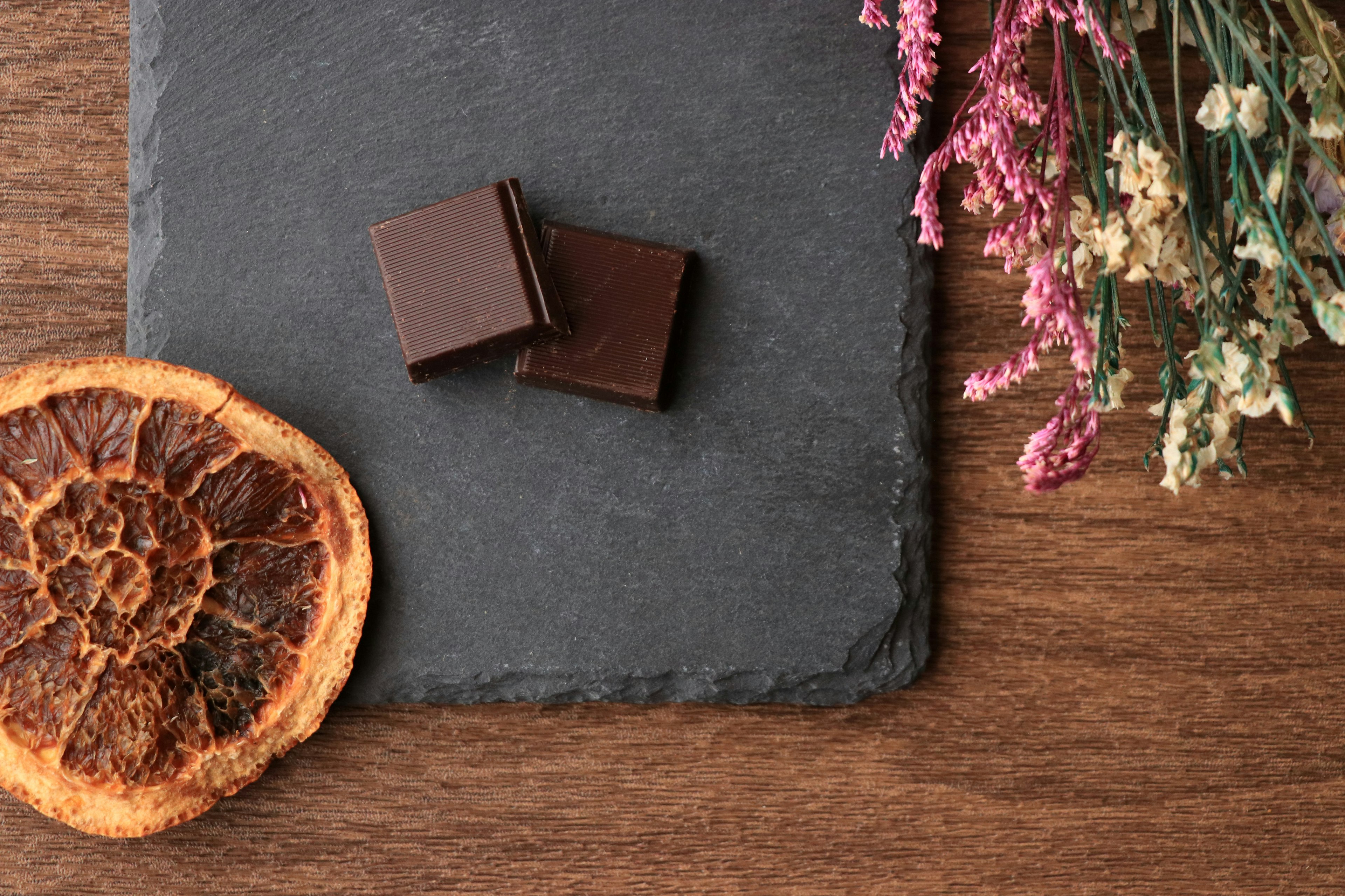 Arreglo de trozos de chocolate negro y una rodaja de naranja seca sobre un plato de pizarra