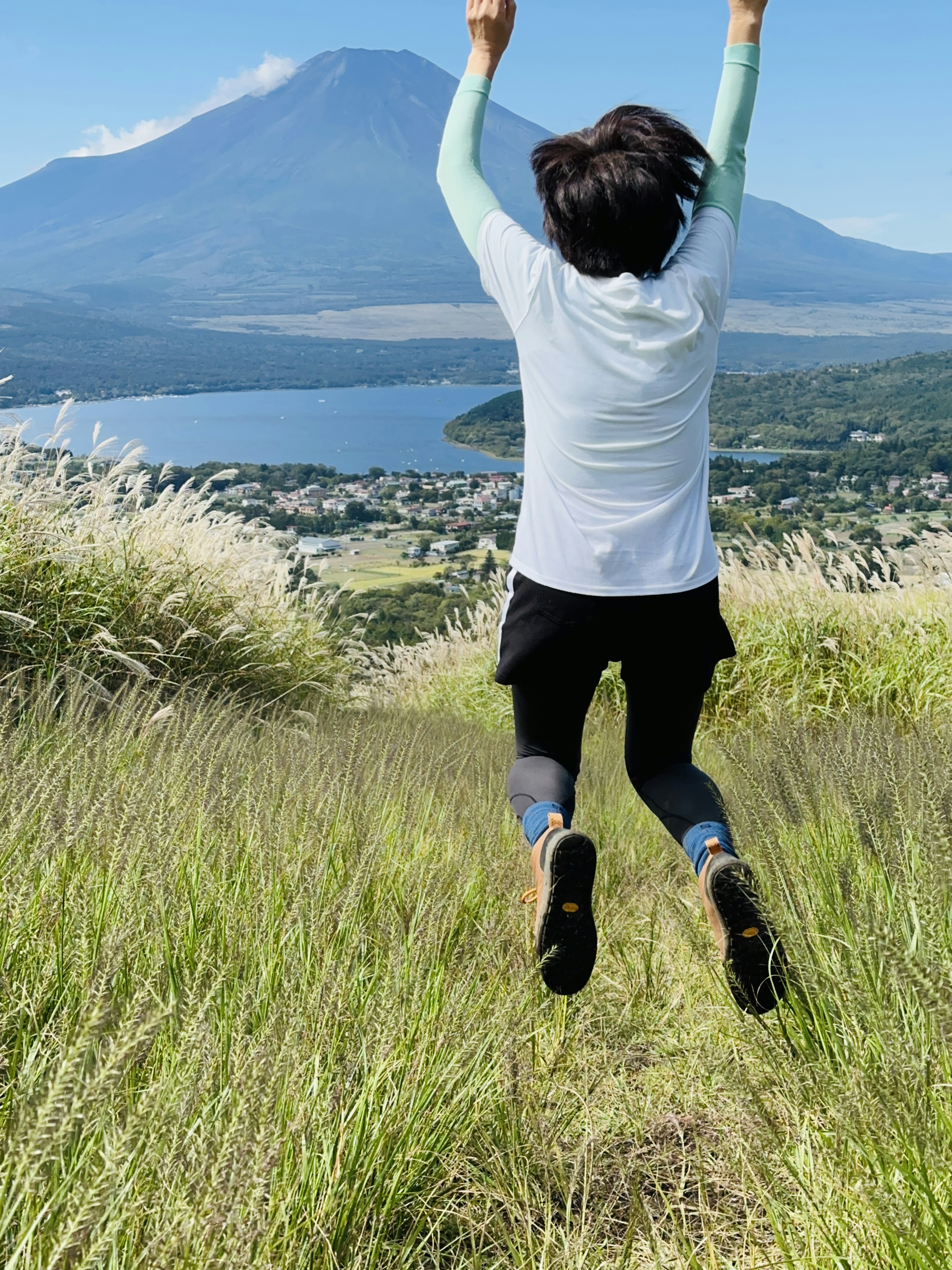 Personne sautant dans l'herbe verte avec le mont Fuji en arrière-plan