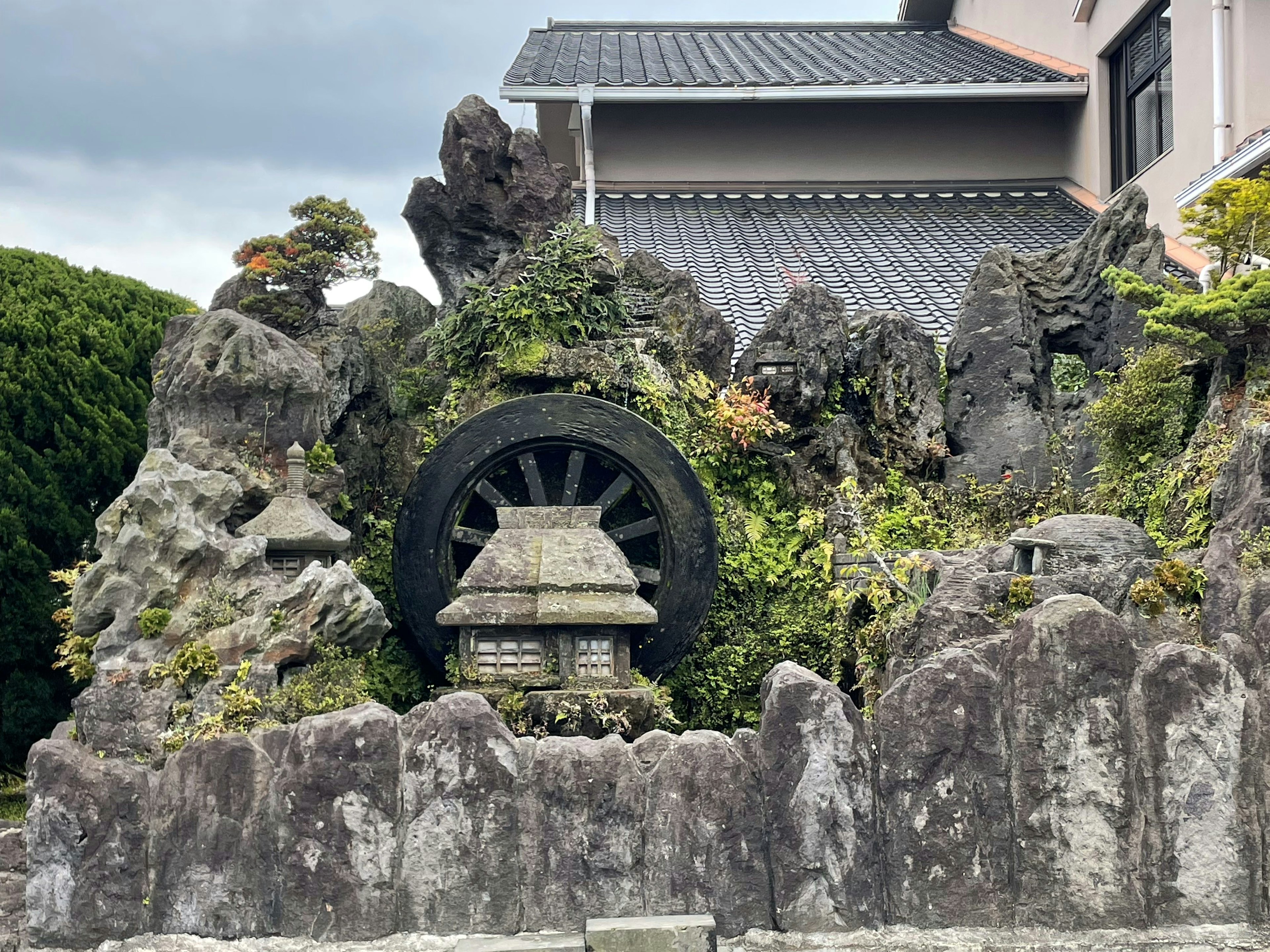 Scenic stone garden with water wheel and lush greenery