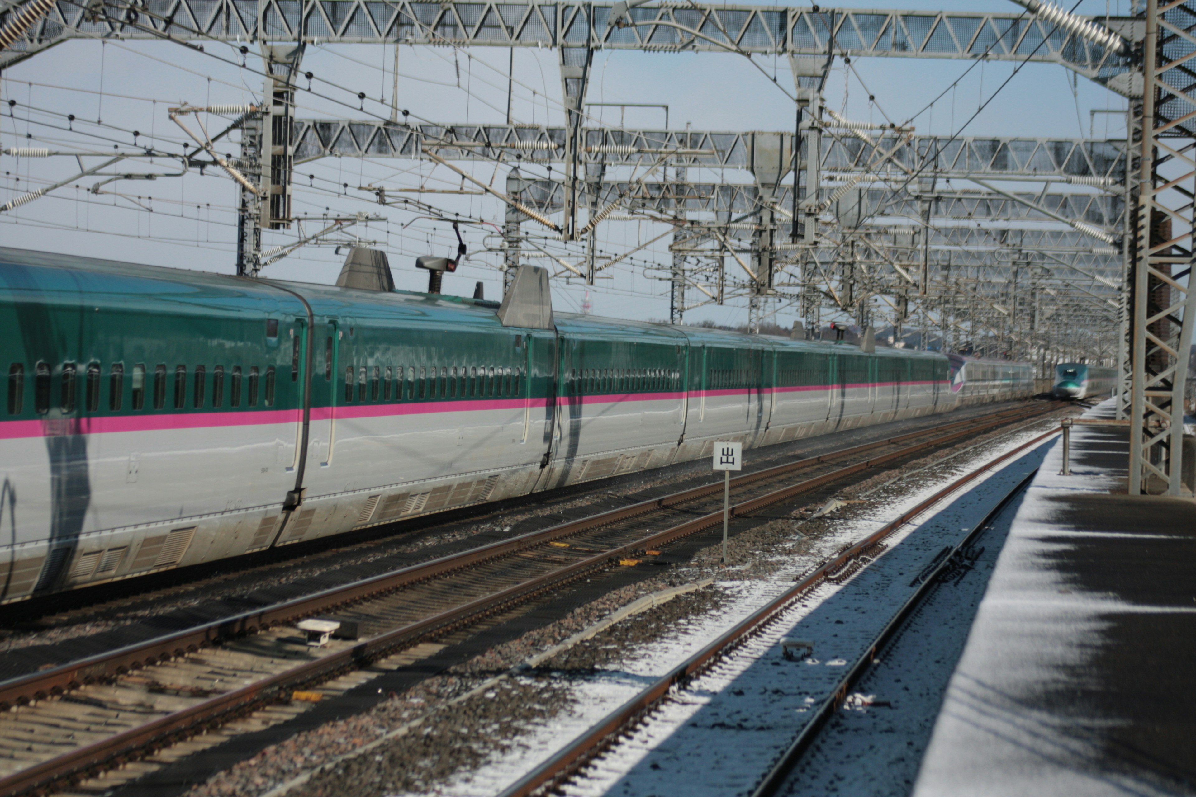 Tampilan samping kereta Shinkansen yang melintasi rel bersalju