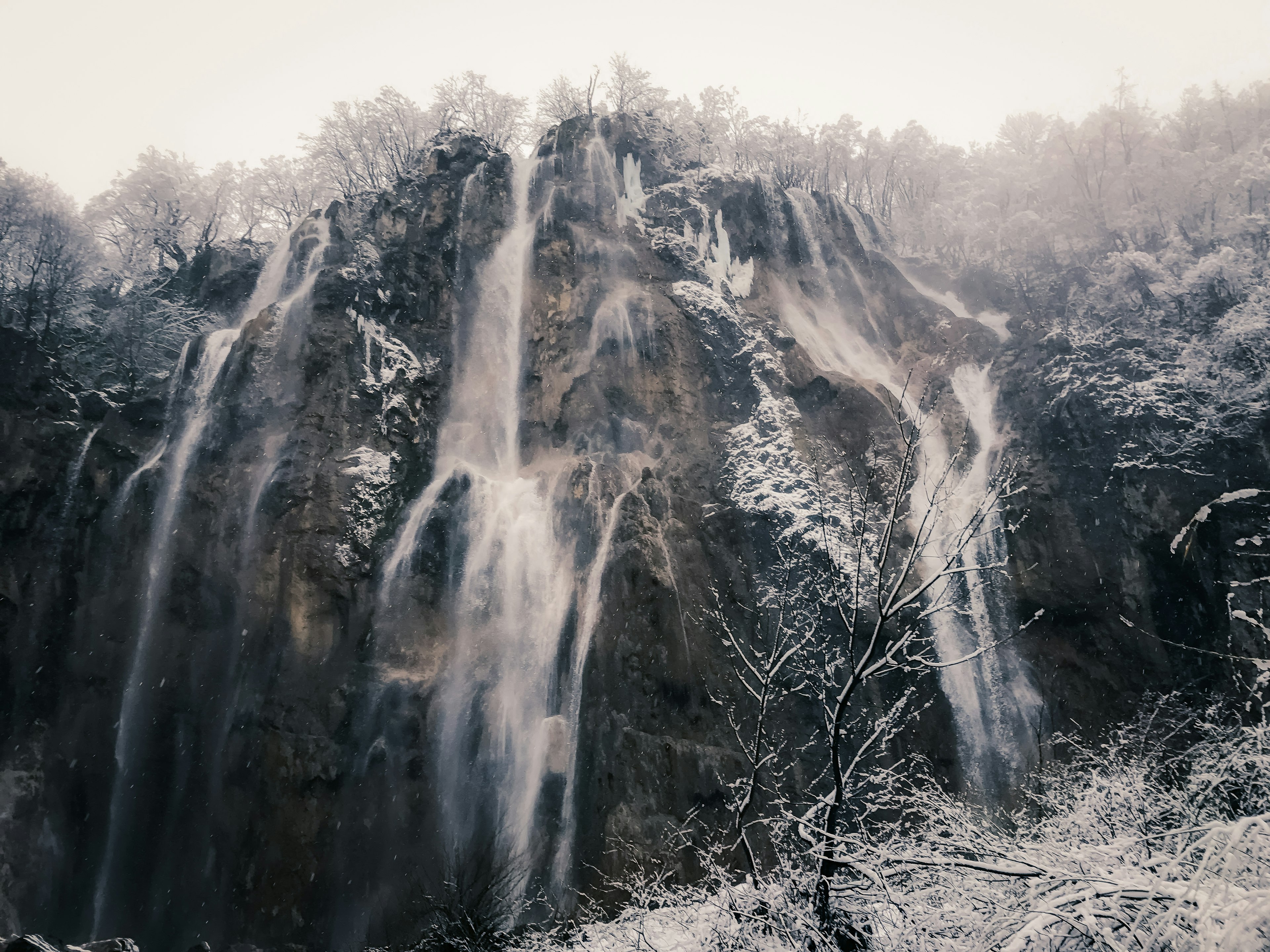 Pemandangan indah air terjun mengalir melalui batu-batu yang tertutup salju