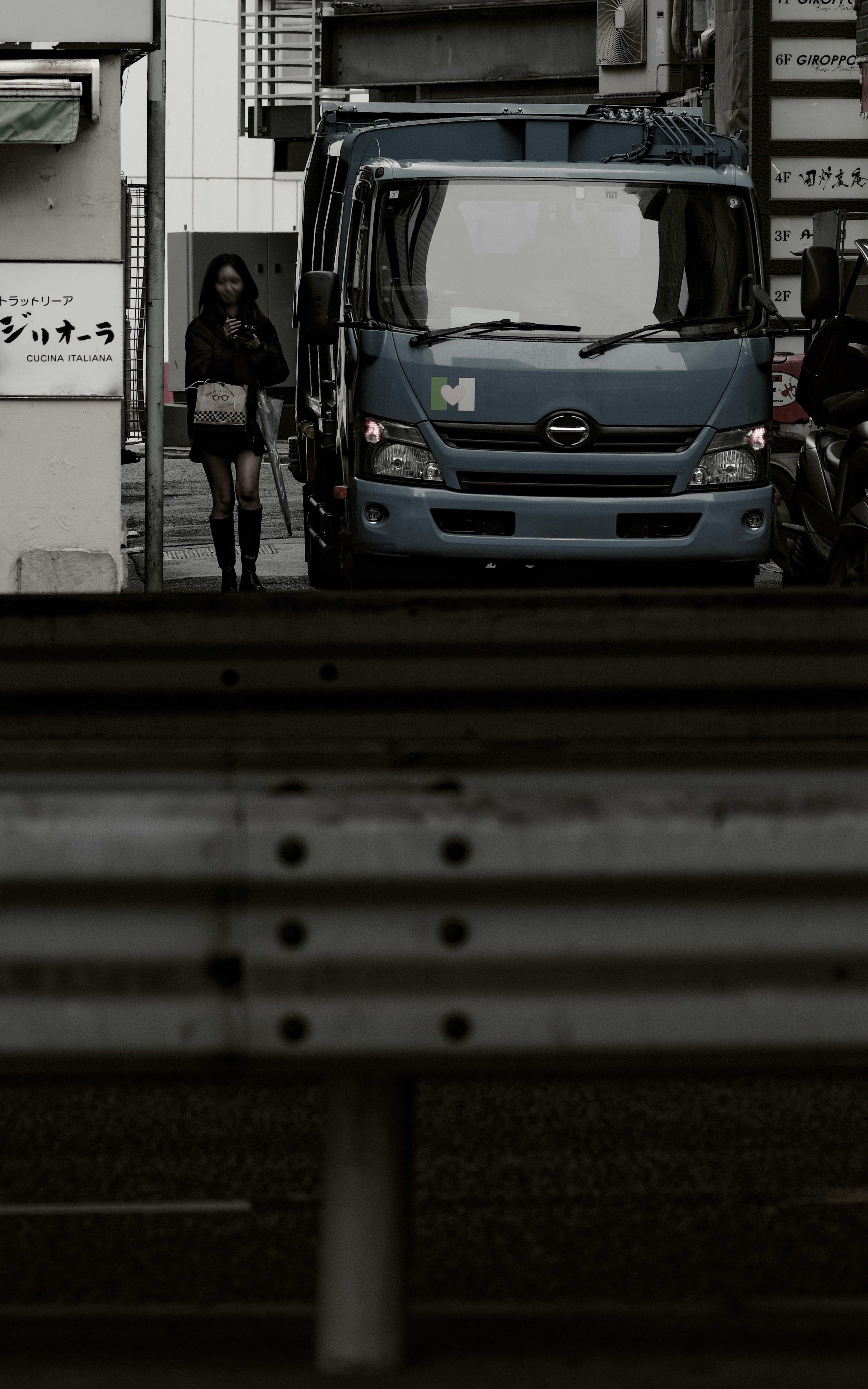 A woman walking in the city with a blue truck in the background