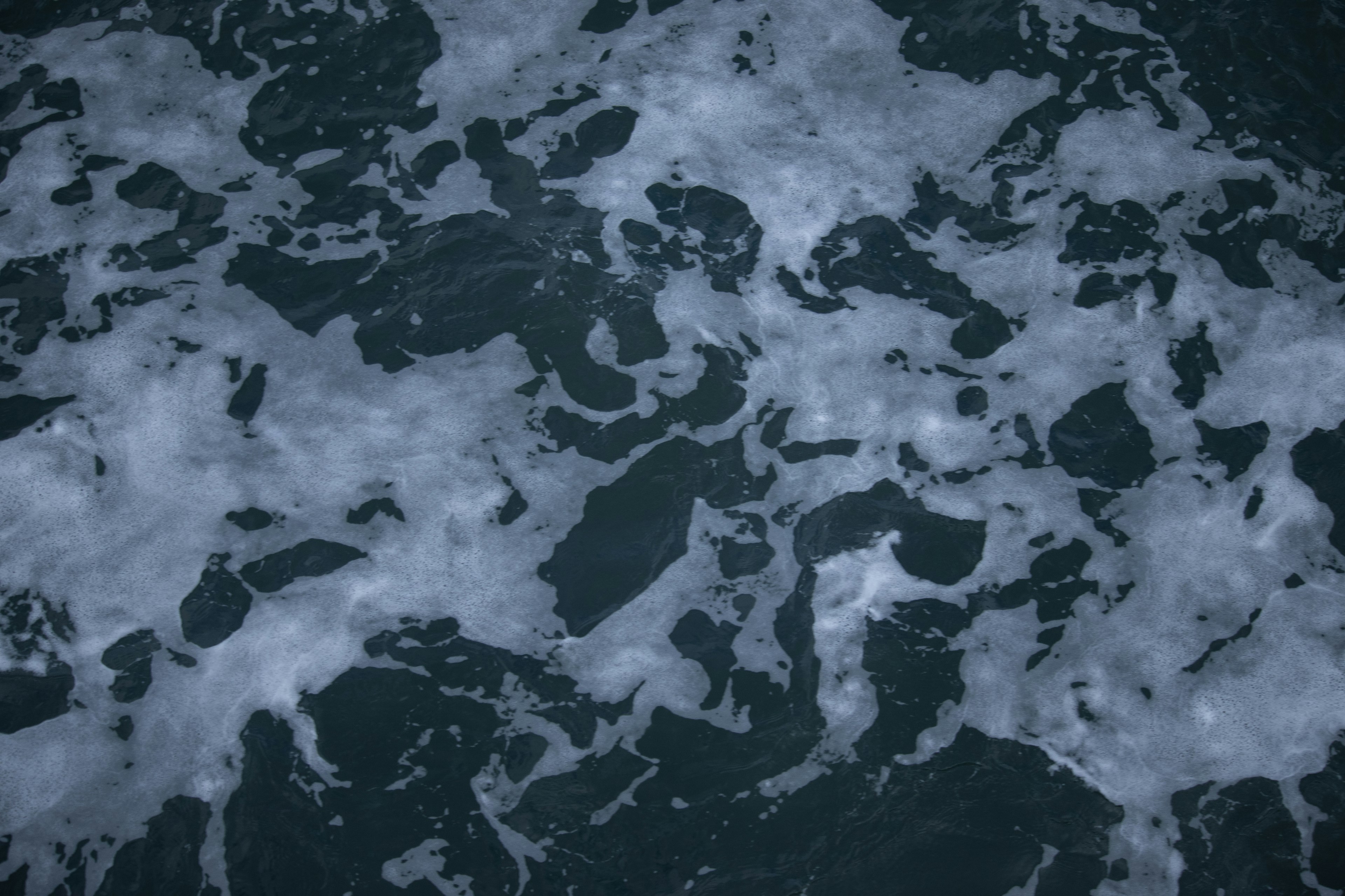 Patterns of foam and water on a dark ocean surface