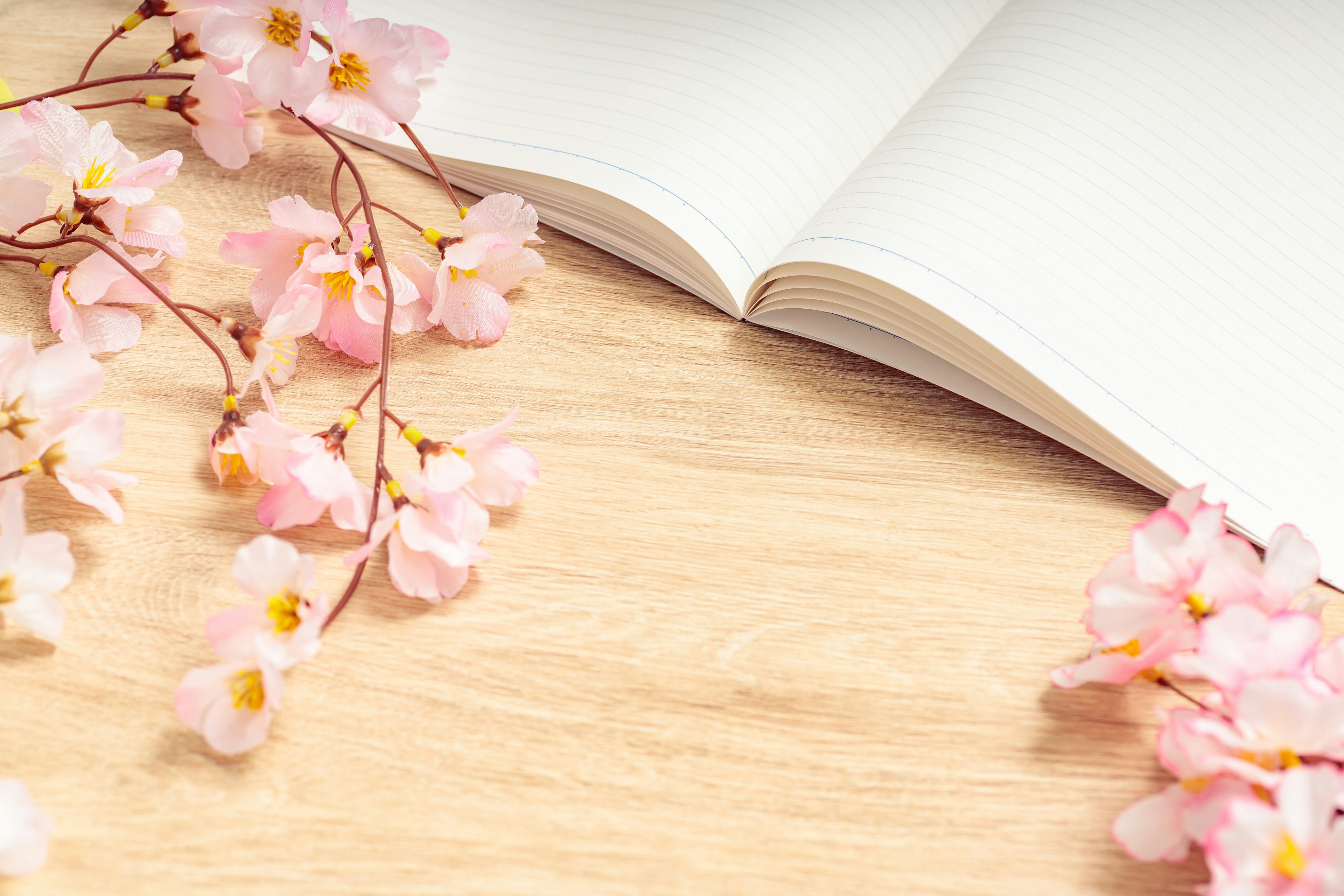 Open notebook with cherry blossom branches on a wooden table